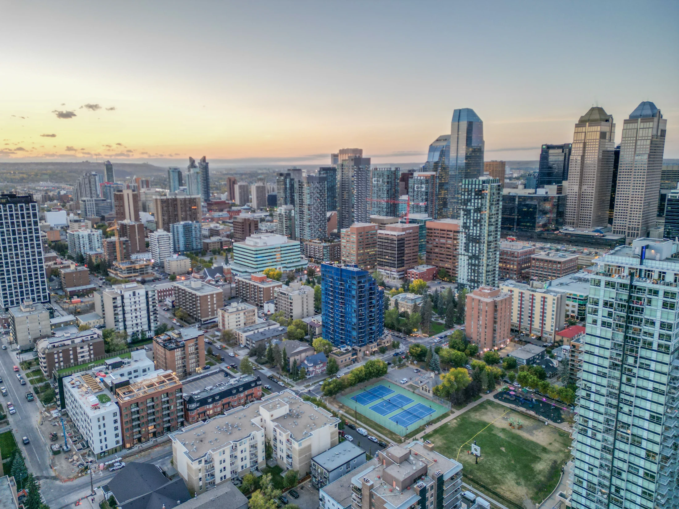 Aerial of downtown towers with a sports court and park in front