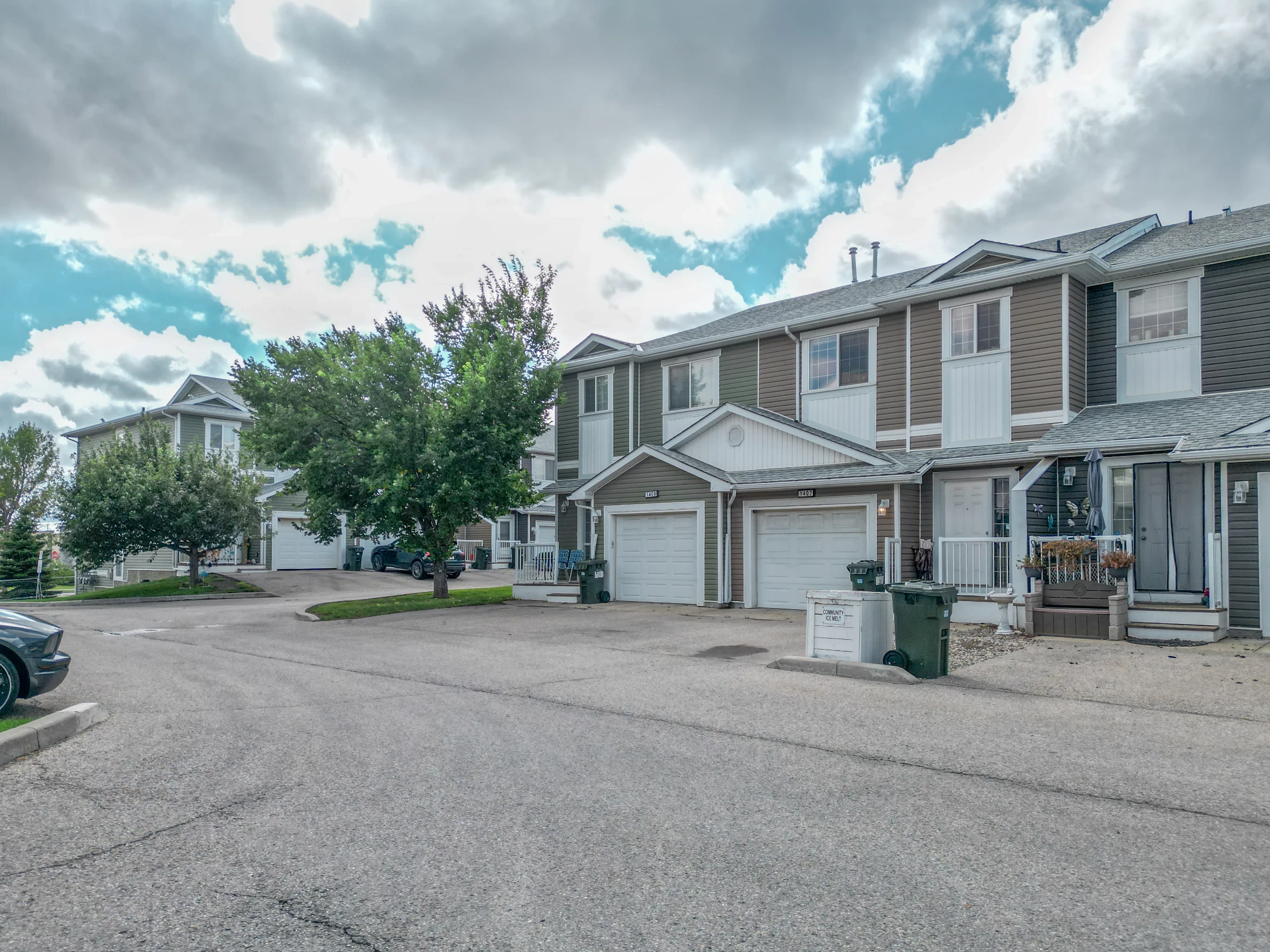 Row of townhomes with single front garages and young trees