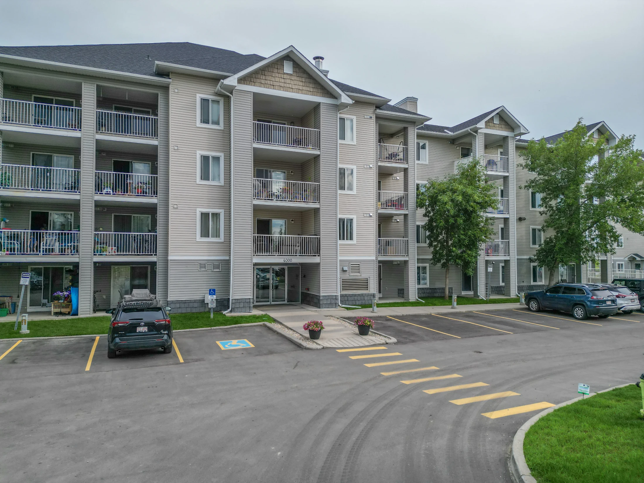 Low-rise condo building with balconies above a landscaped parking lot