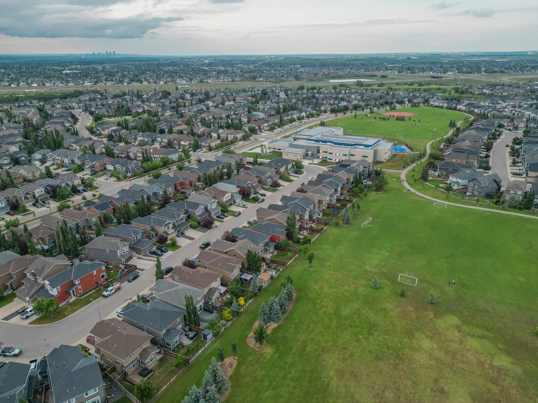 Aerial view of two-storey homes and green space in a northwest Calgary suburb