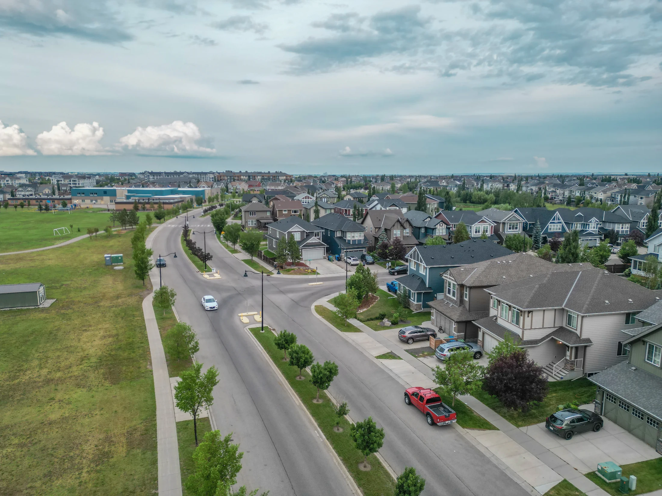 A residential street and open green space in a newer Calgary suburb