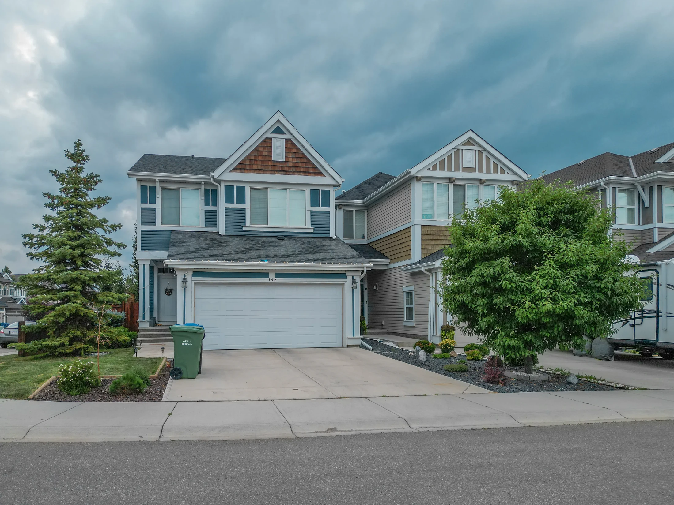 A two-storey home with a double garage and young trees on a Calgary street
