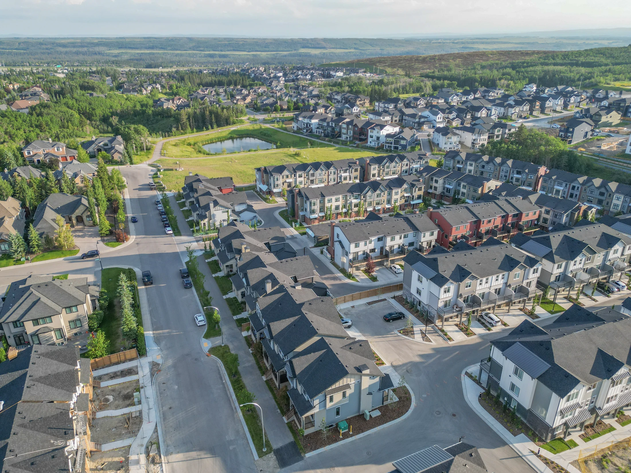 Aerial of townhome rows and two-storey homes on a hillside