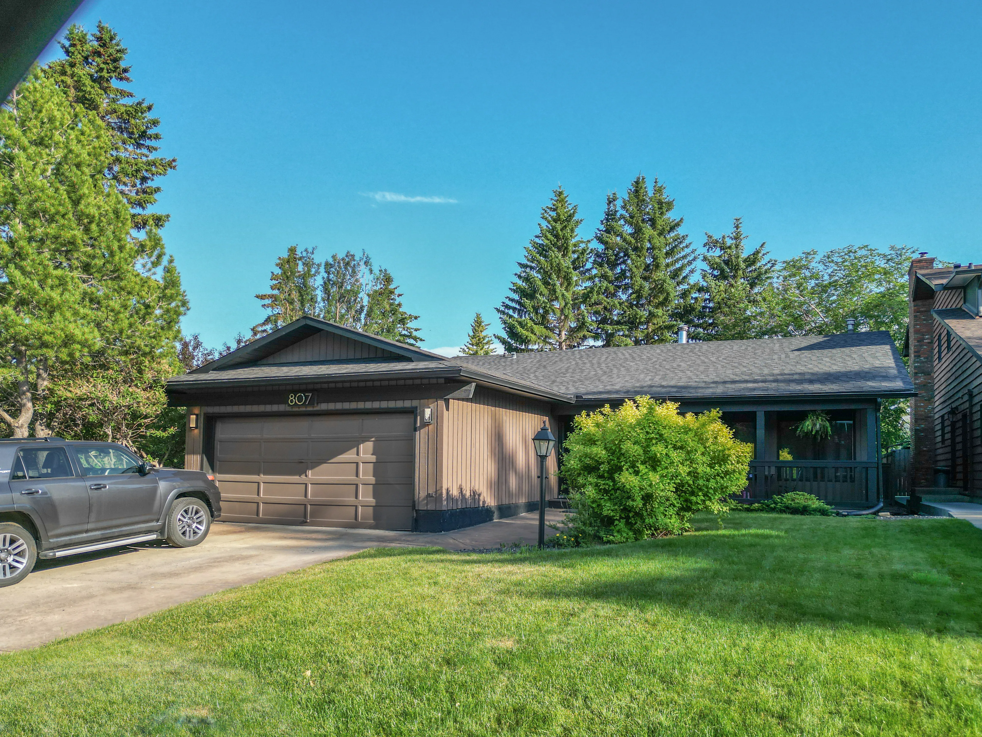 Bungalow with a front garden and mature evergreens on a quiet street