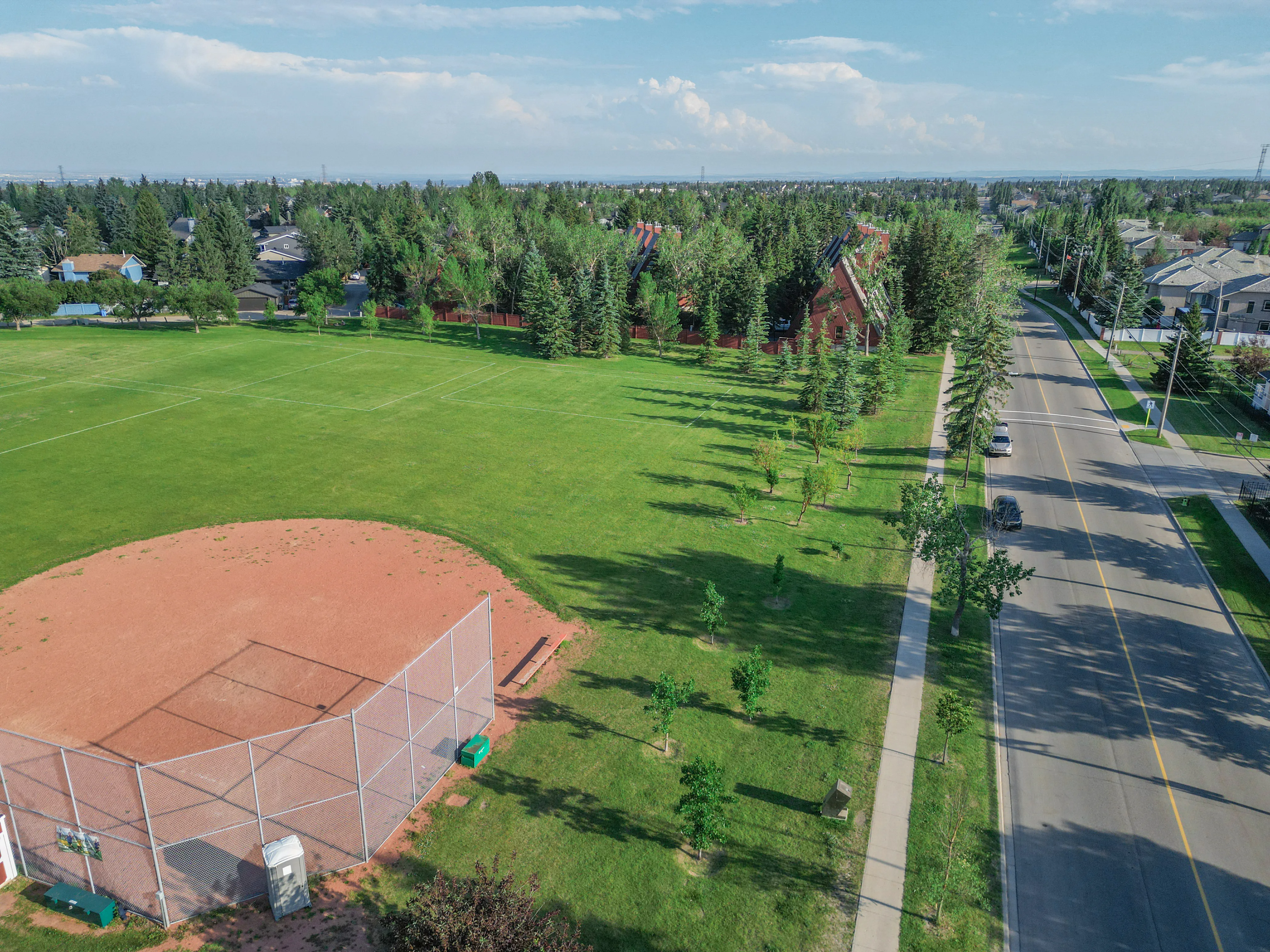 Grassy park with a ball diamond and mature trees