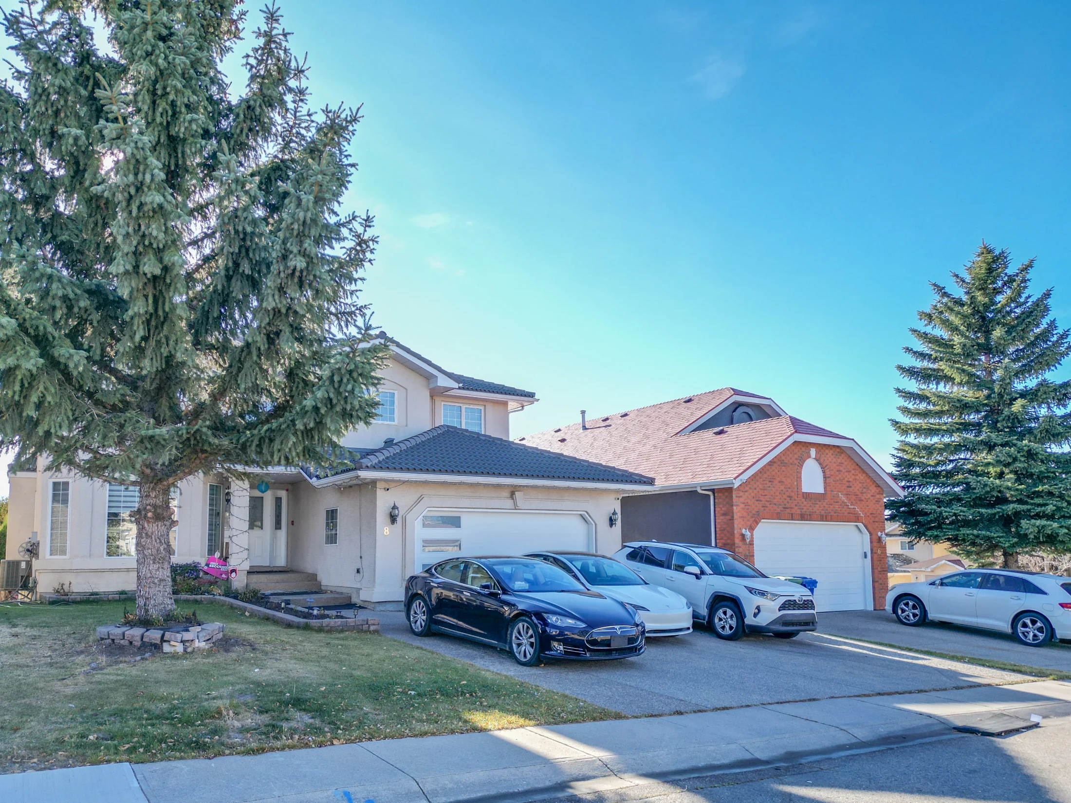 Two-storey home with a double garage and a large spruce tree
