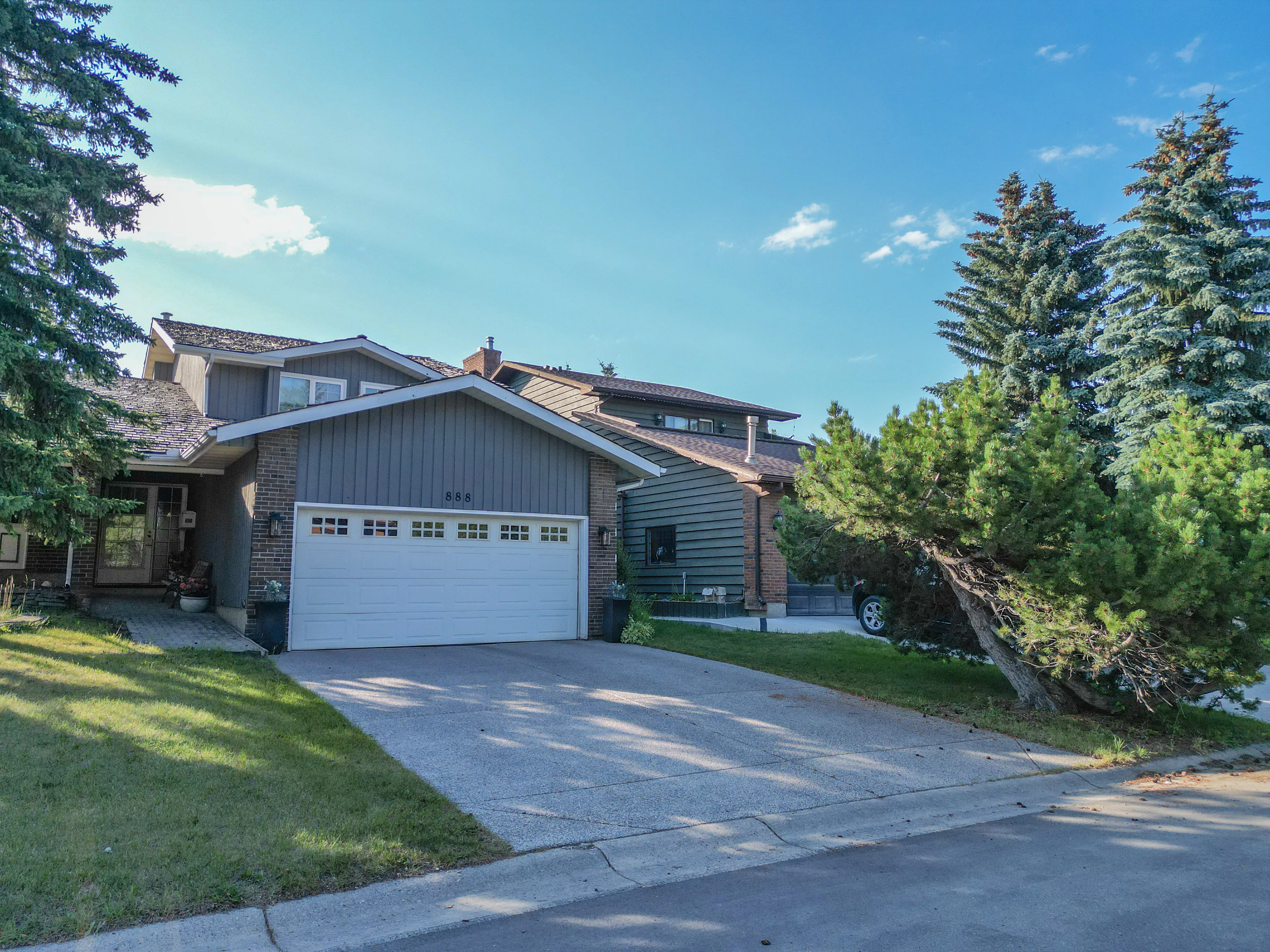 Older home with a front garage set among tall evergreens