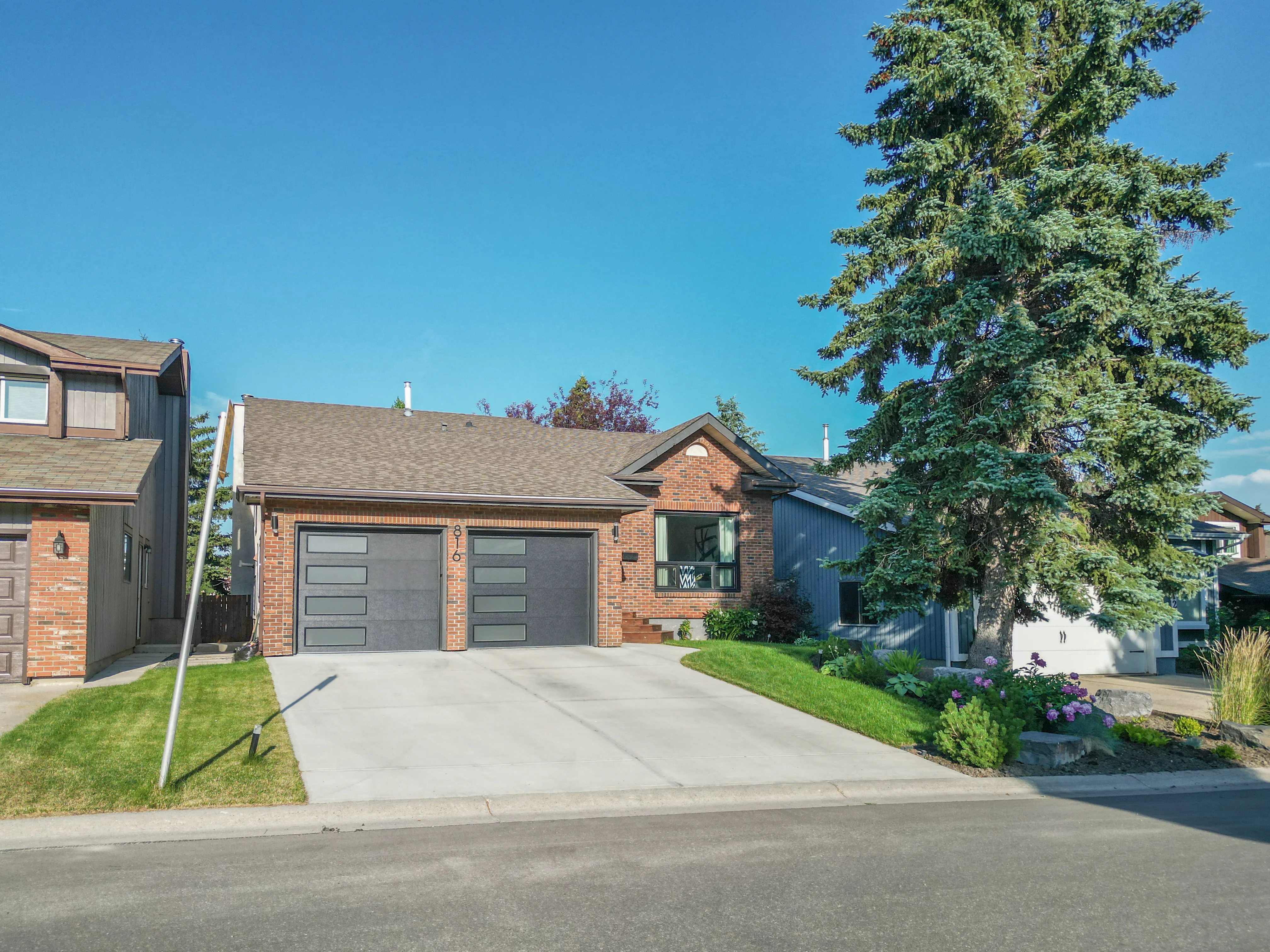 Bungalow with a double garage and a tall spruce tree