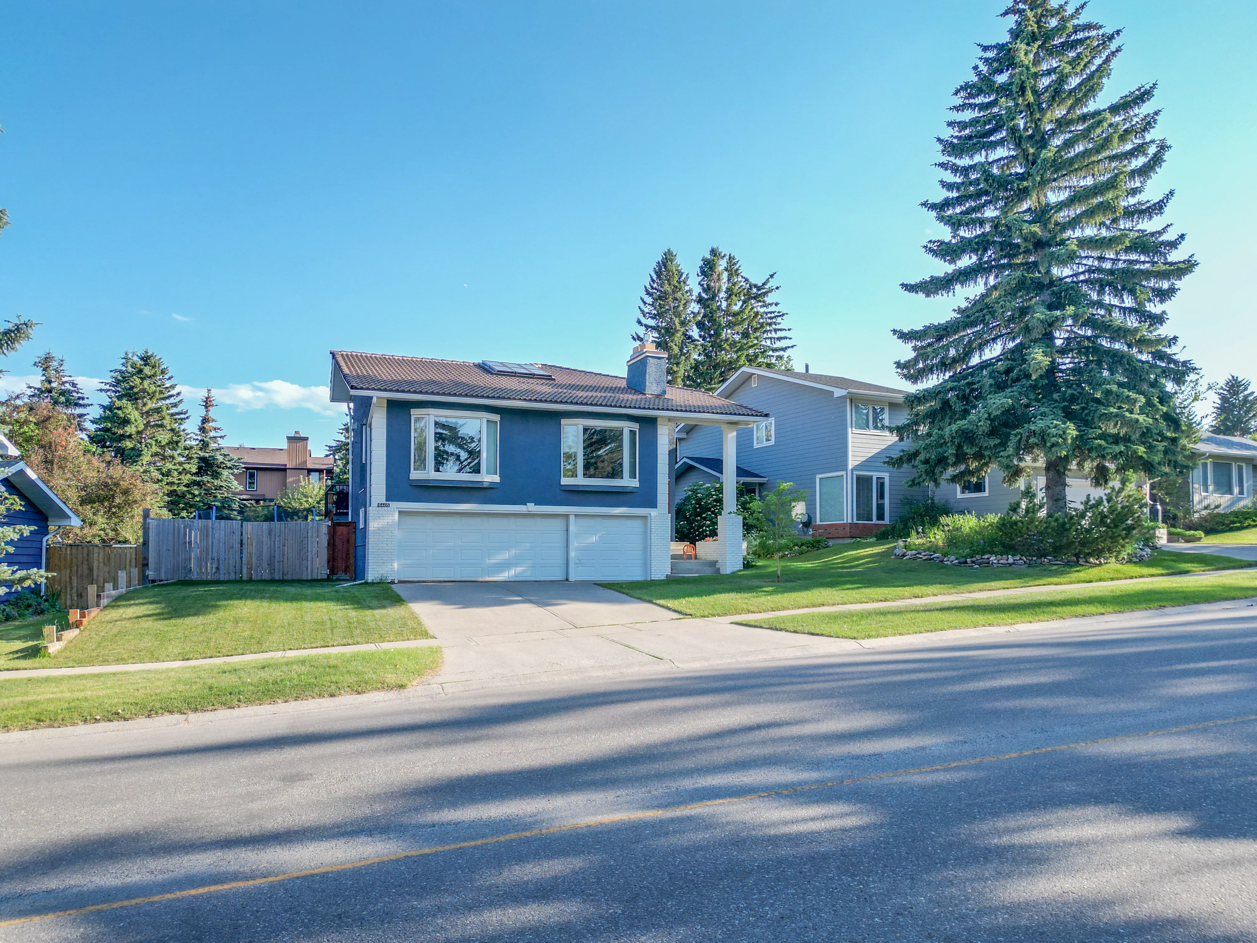 Two-storey home on a quiet street with tall trees and a wide lawn