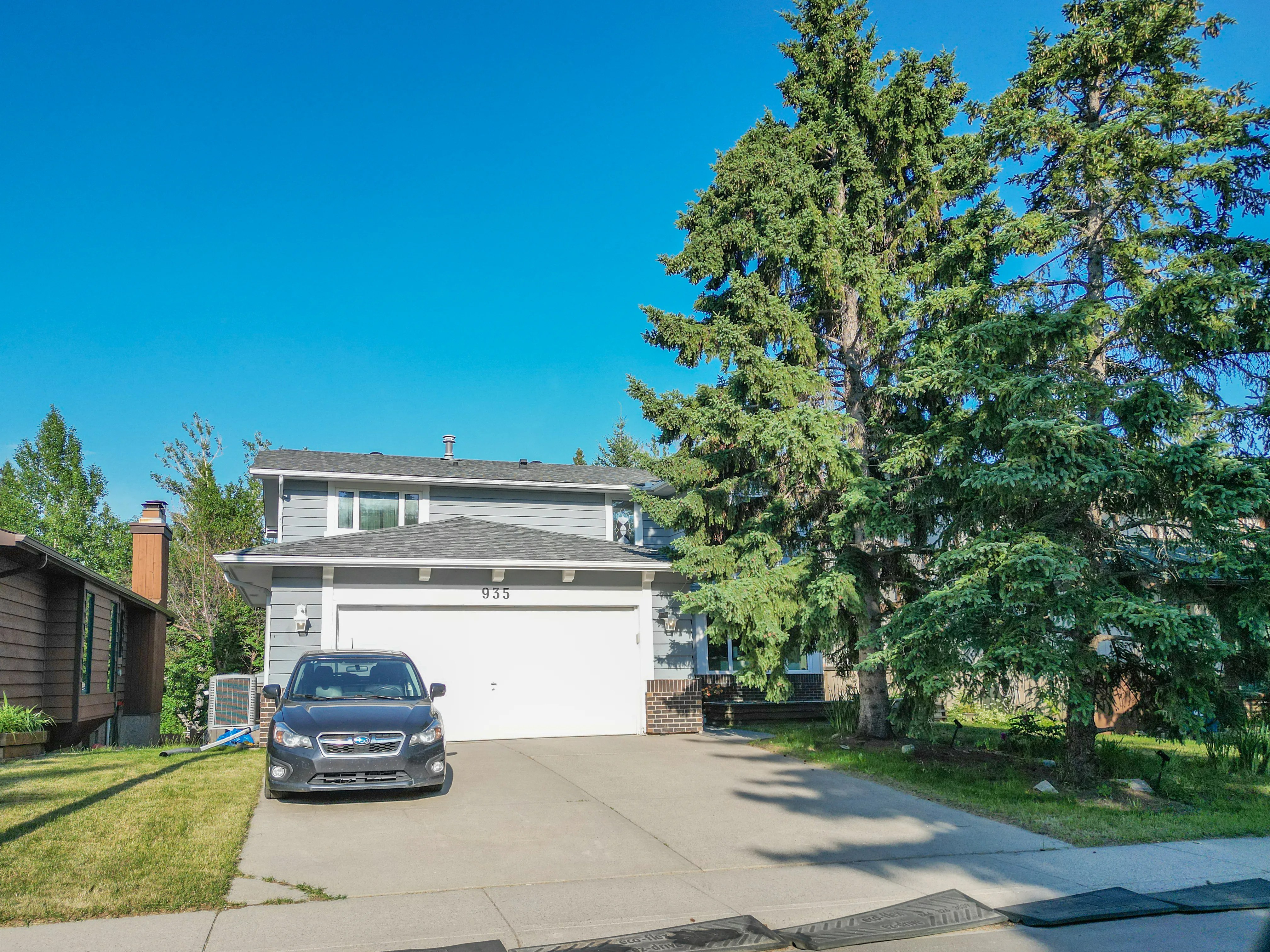 Two-storey home with a white garage among mature trees
