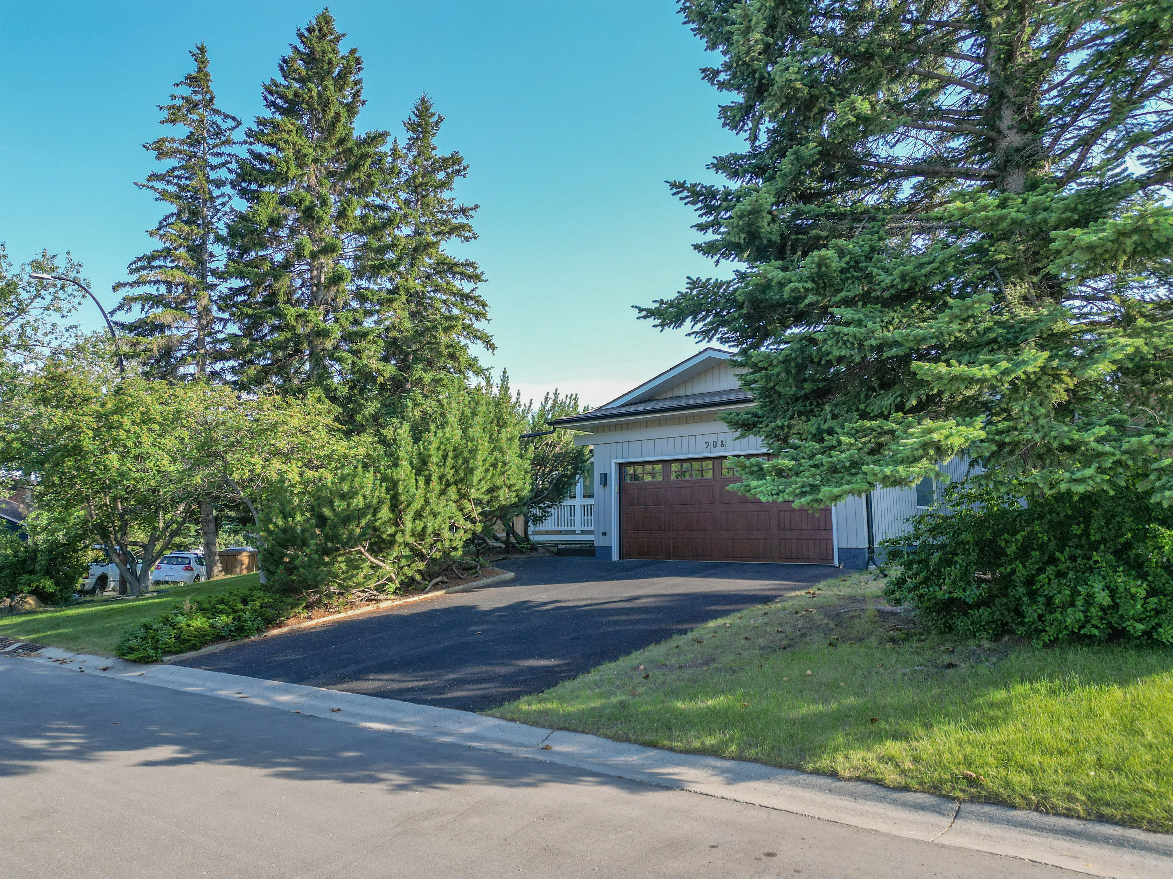 Large home with a long driveway framed by mature spruce trees