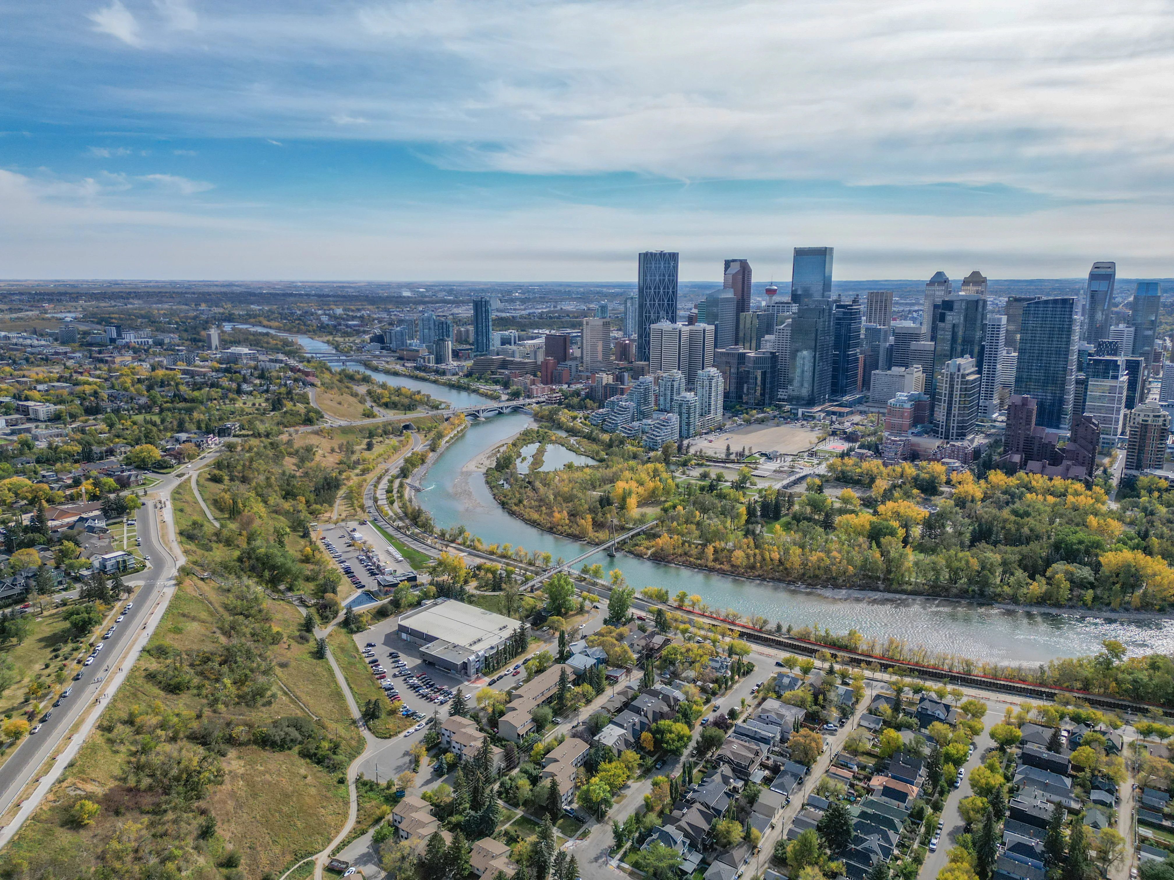 River valley parkland with pathways below a city skyline