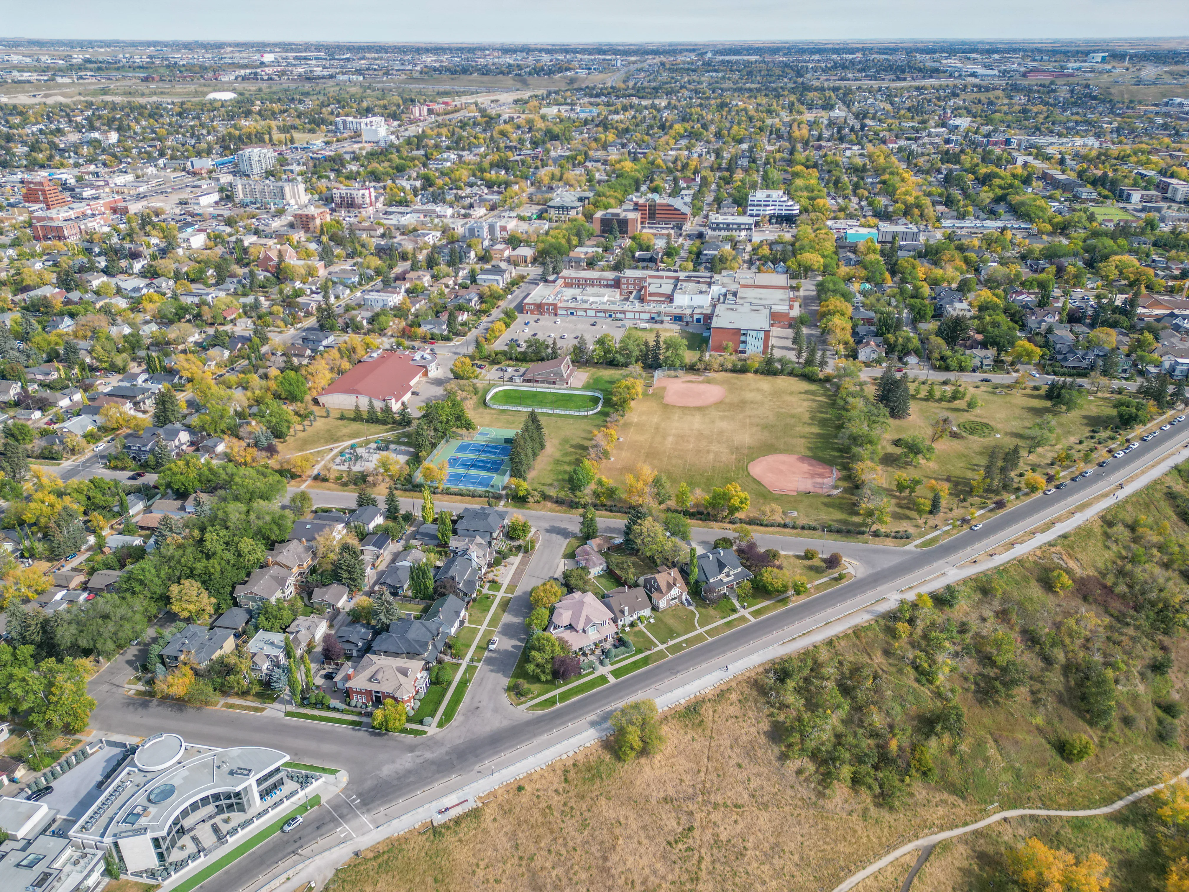 Aerial of a park with a ball diamond surrounded by mature trees and homes
