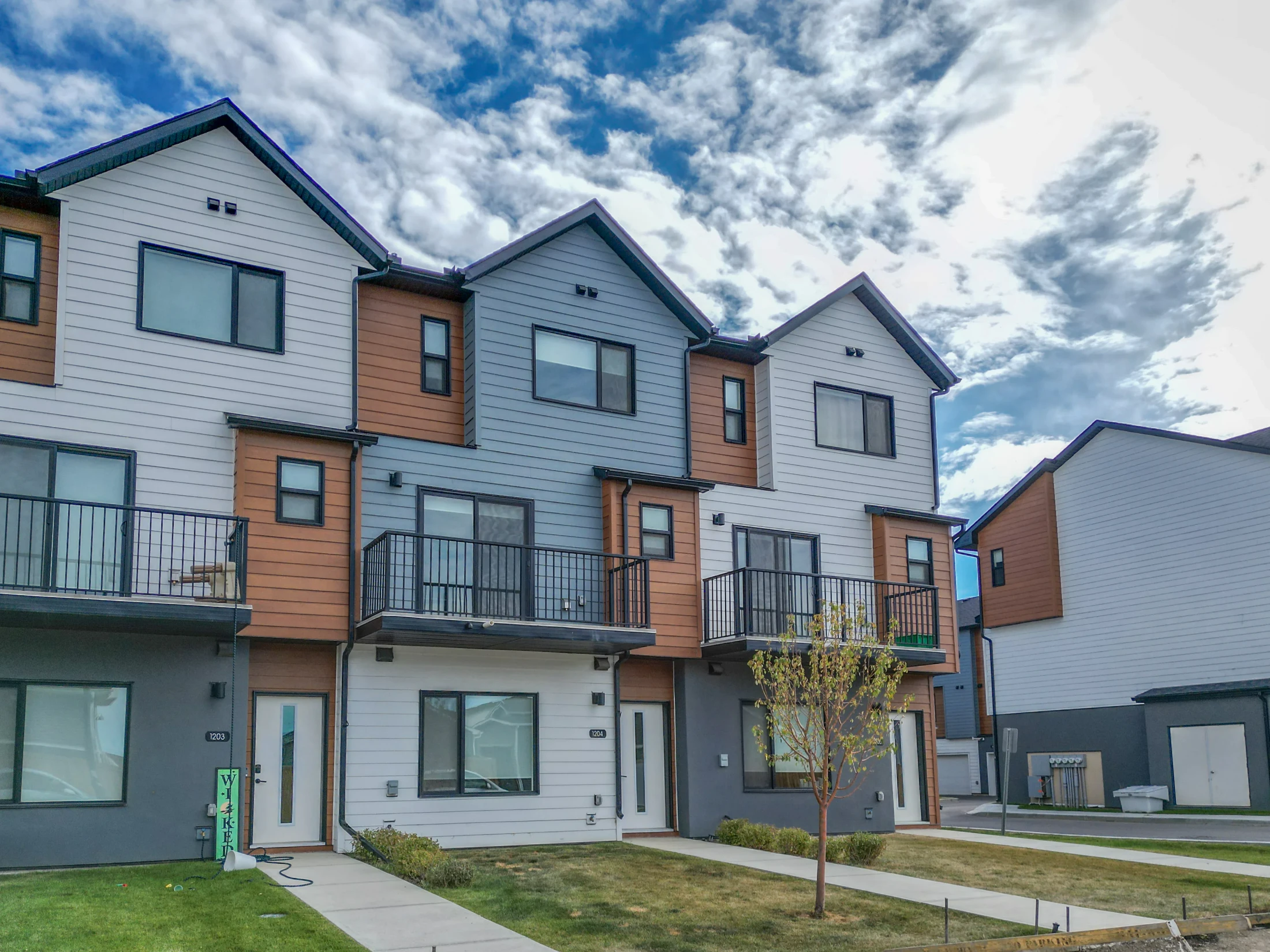 Modern three-storey townhomes with balconies and young street trees