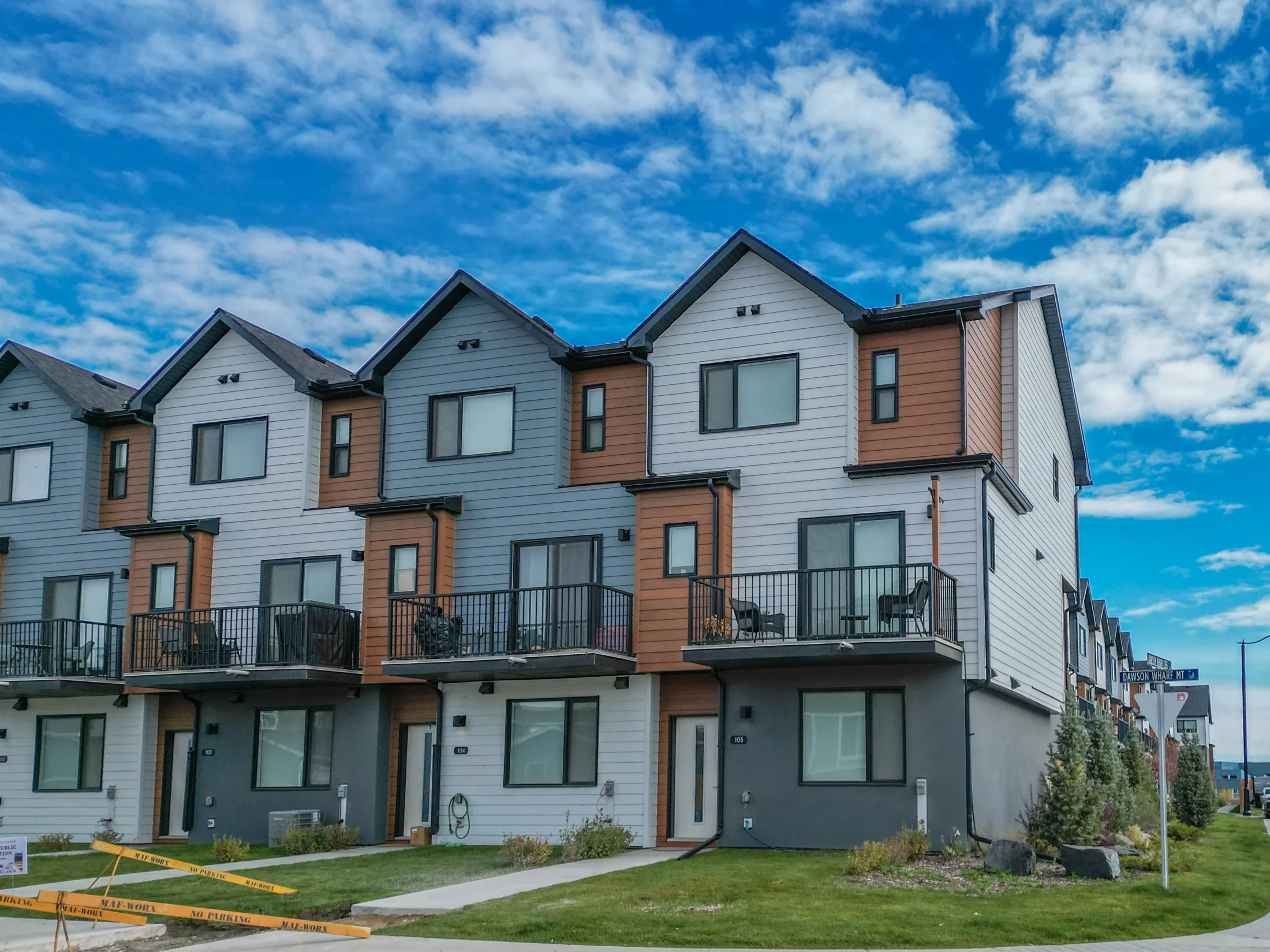 Modern three-storey townhomes with balconies and young trees