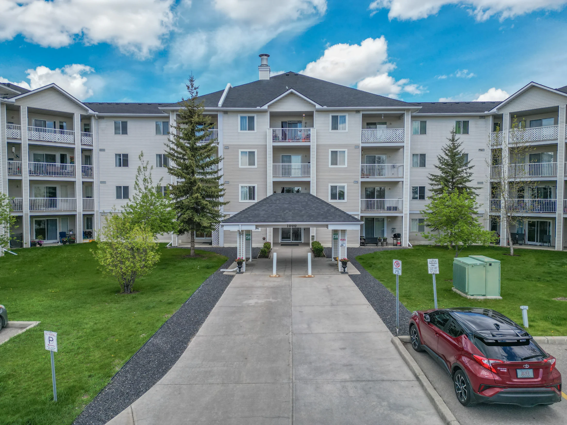 Low-rise condo building with a landscaped lawn and young trees