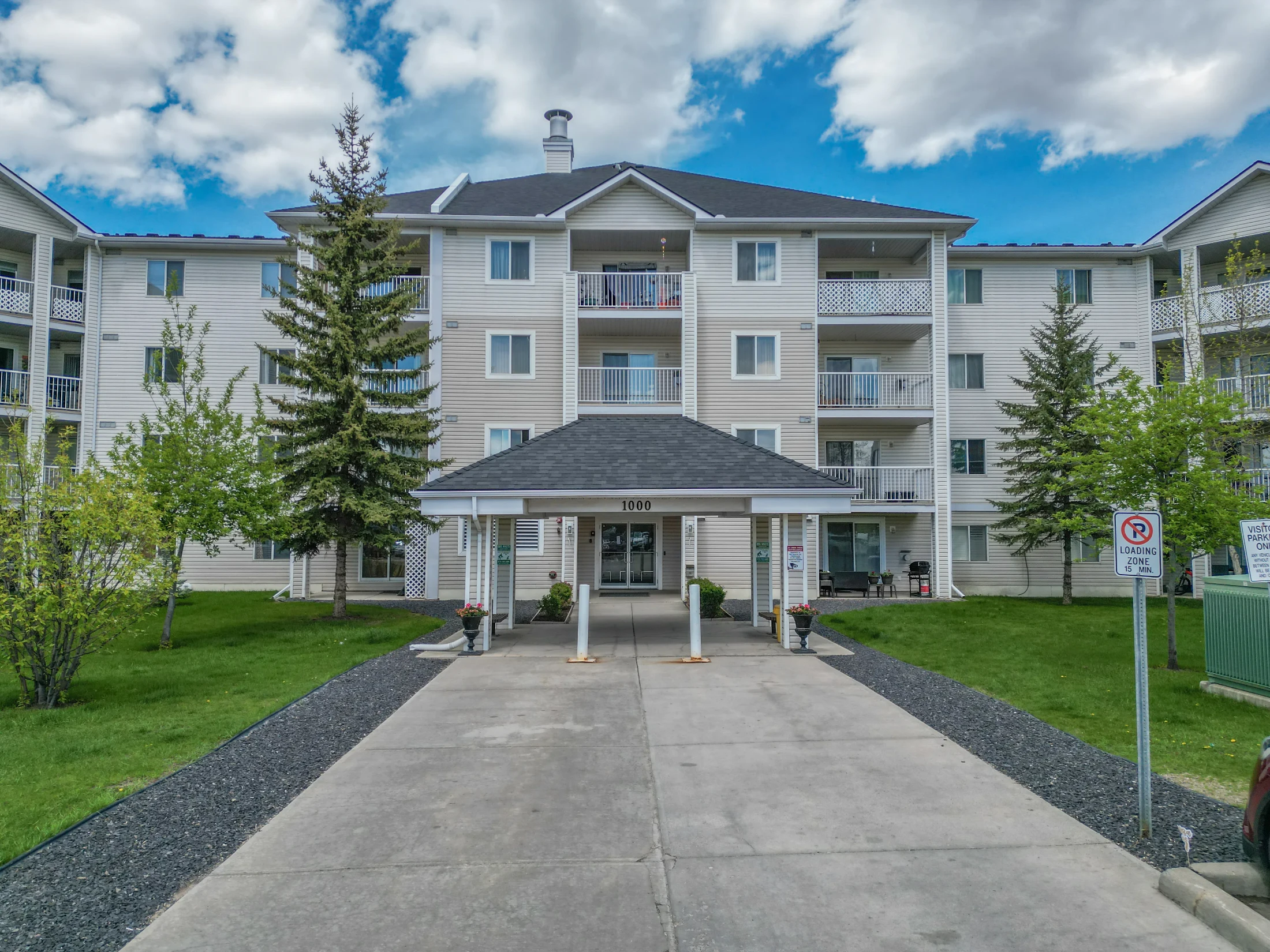 Low-rise condo building with a covered entry and spruce trees