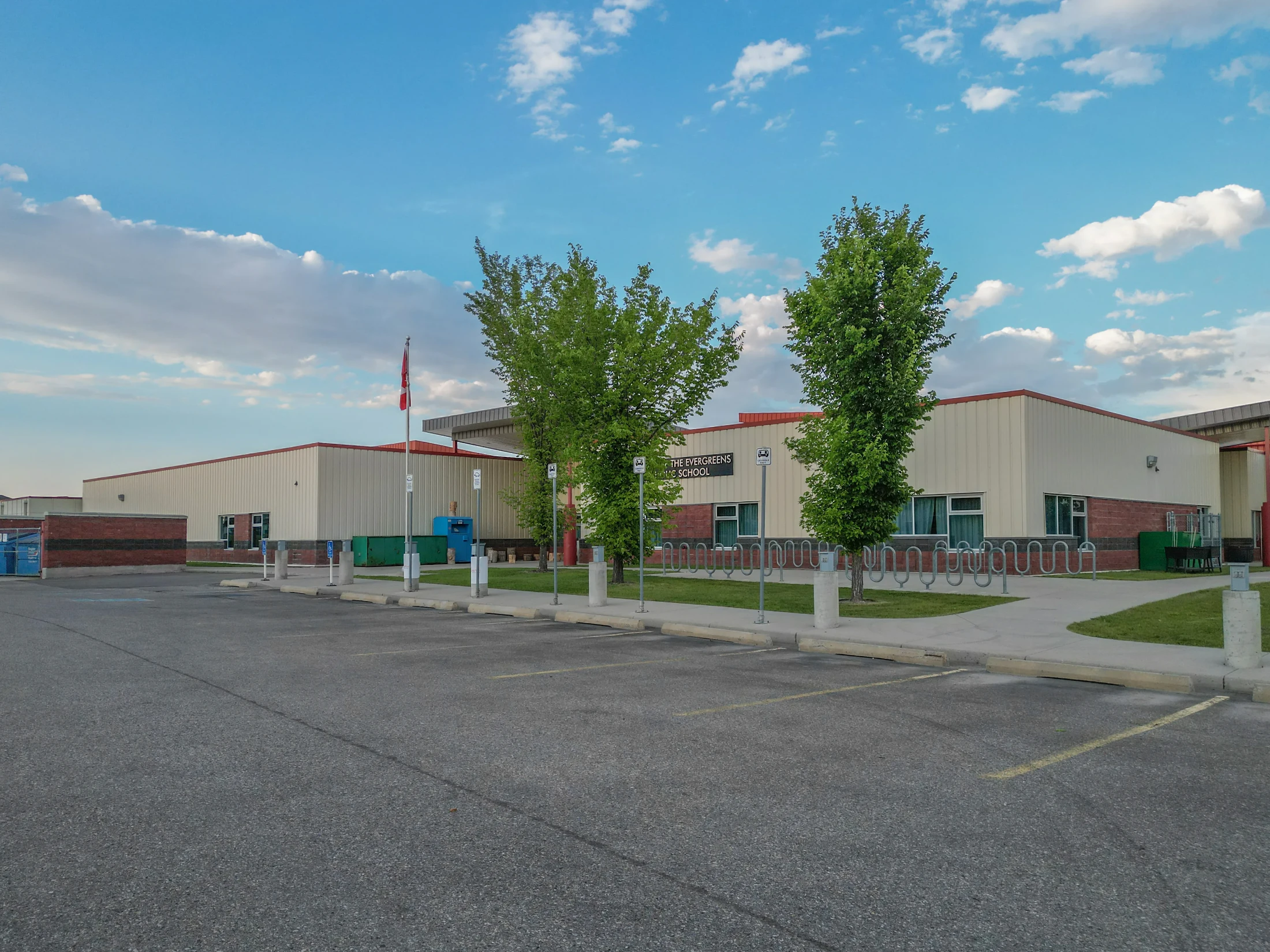 School building with young trees and a parking lot