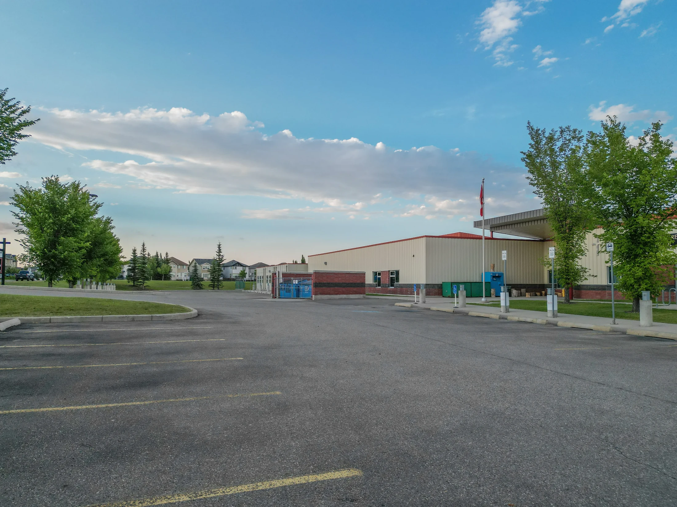 Low school building beside a parking lot and field
