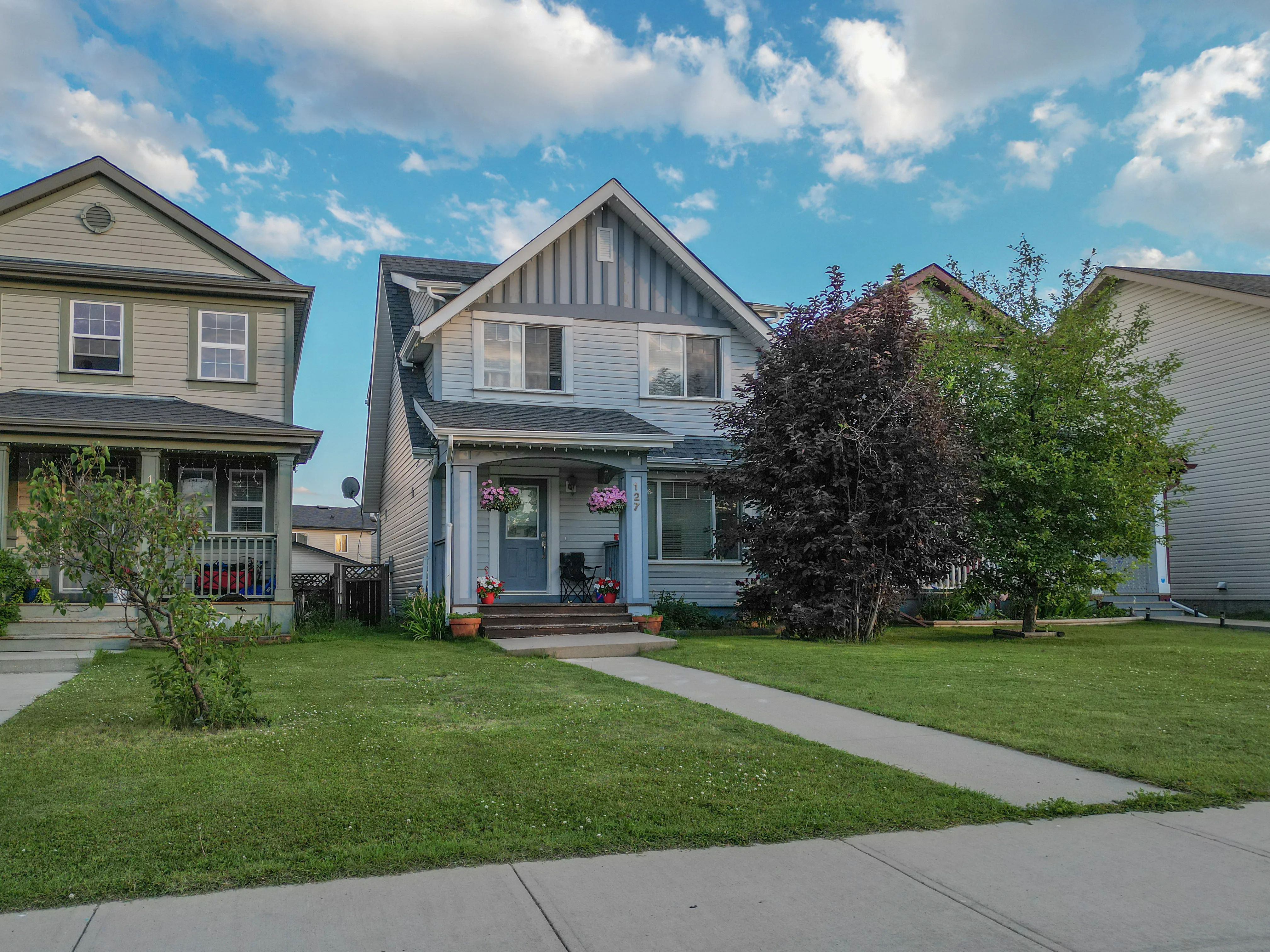 Two-storey home with a front lawn and mature trees on a suburban street
