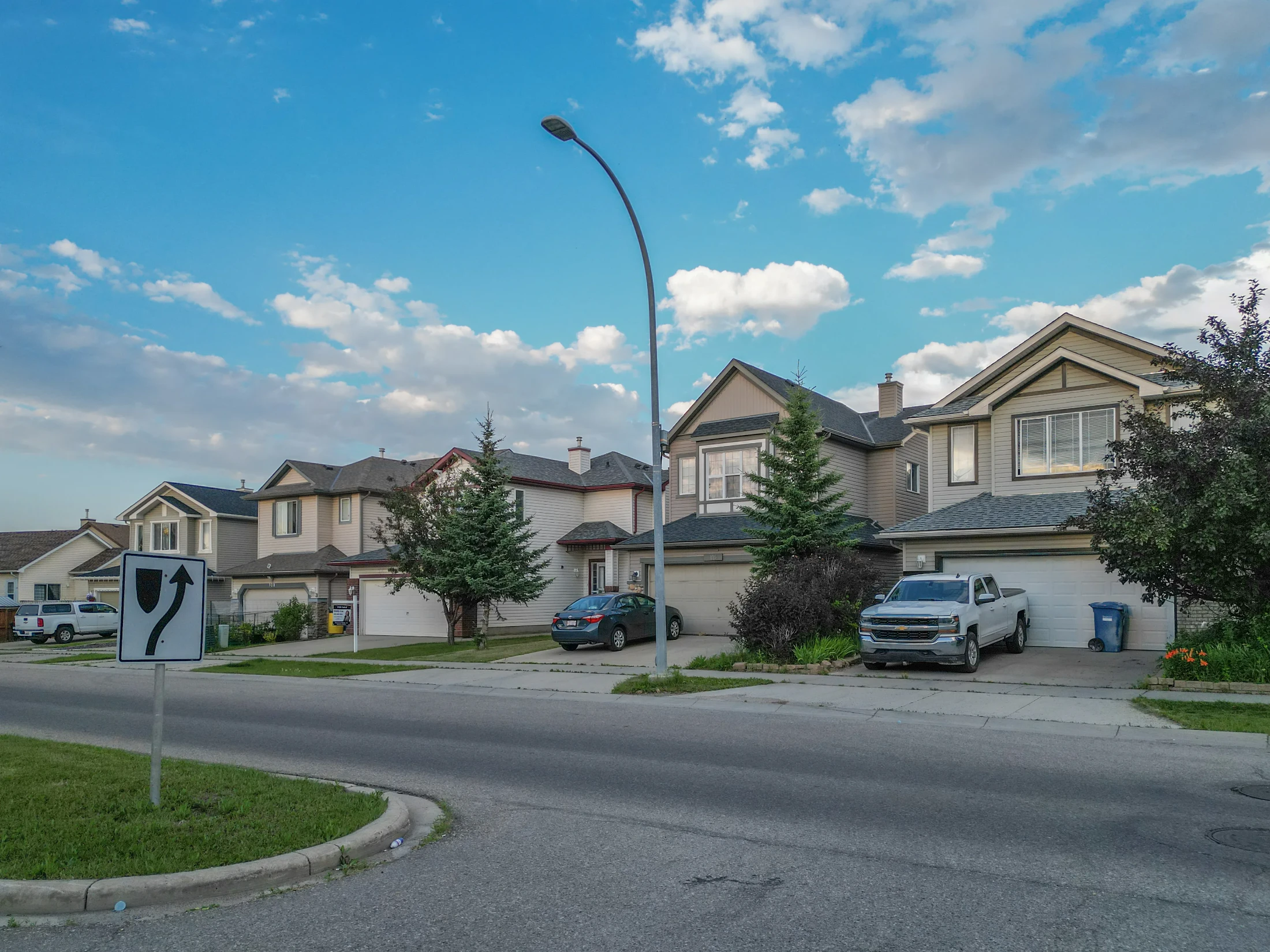 Two-storey homes with lawns and young trees along a curving street