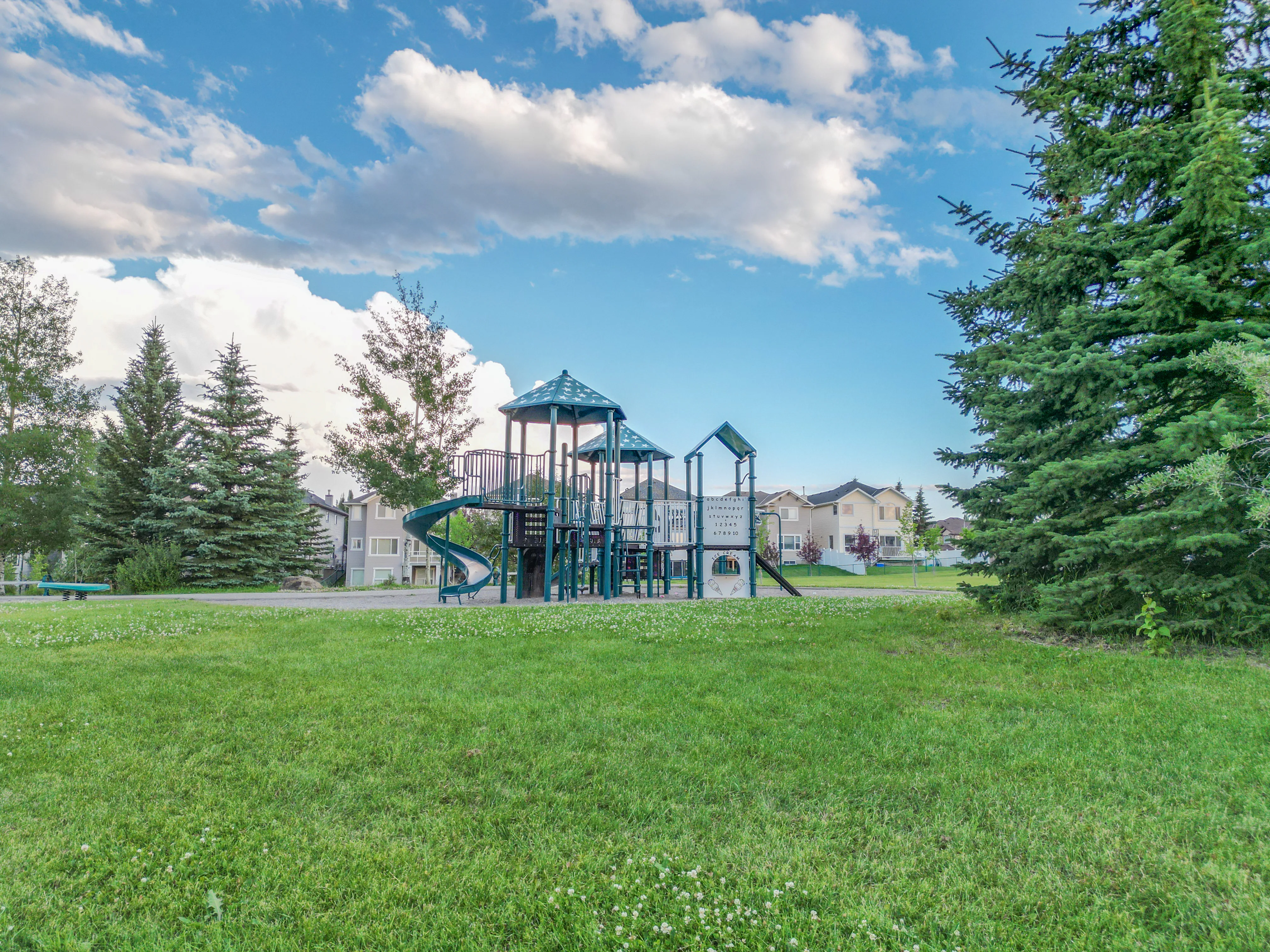 Playground beside a green field and spruce trees