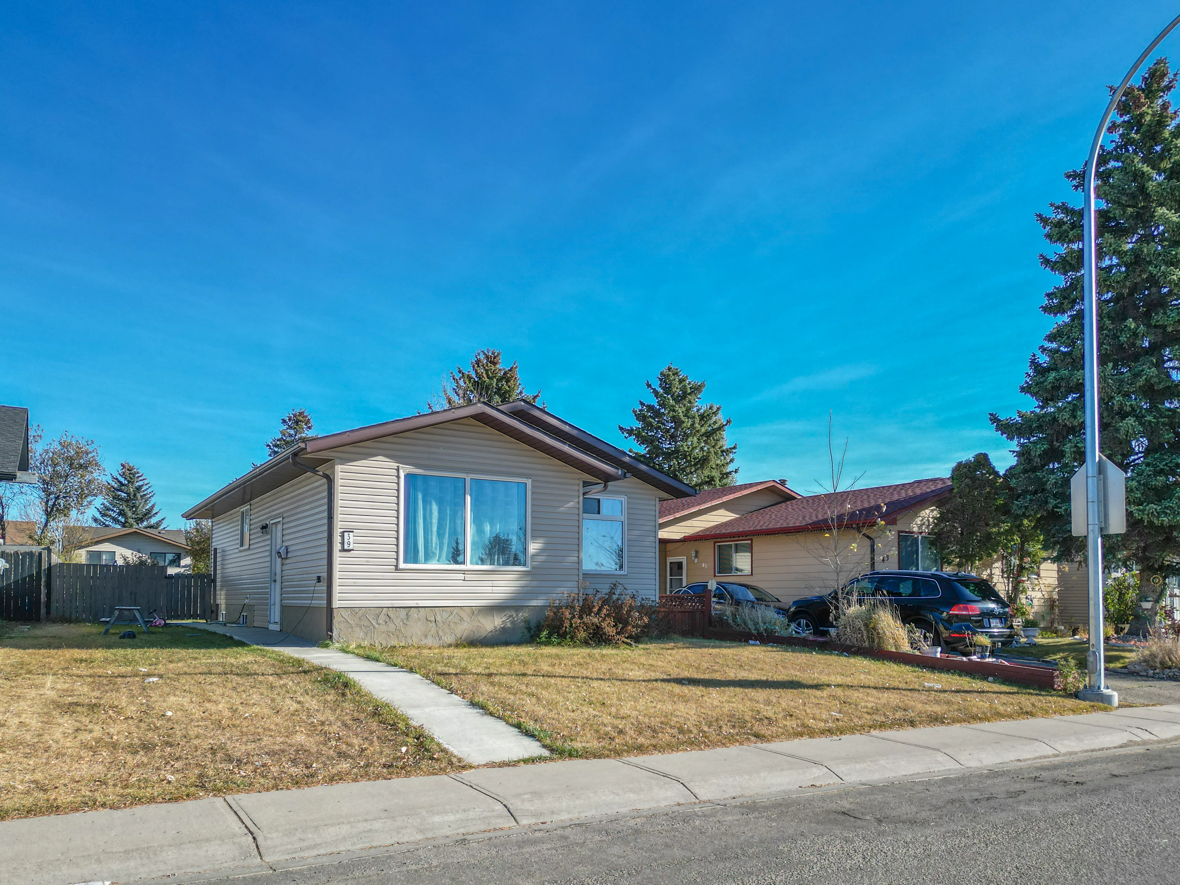 Bungalow with a lawn and mature trees on a residential street