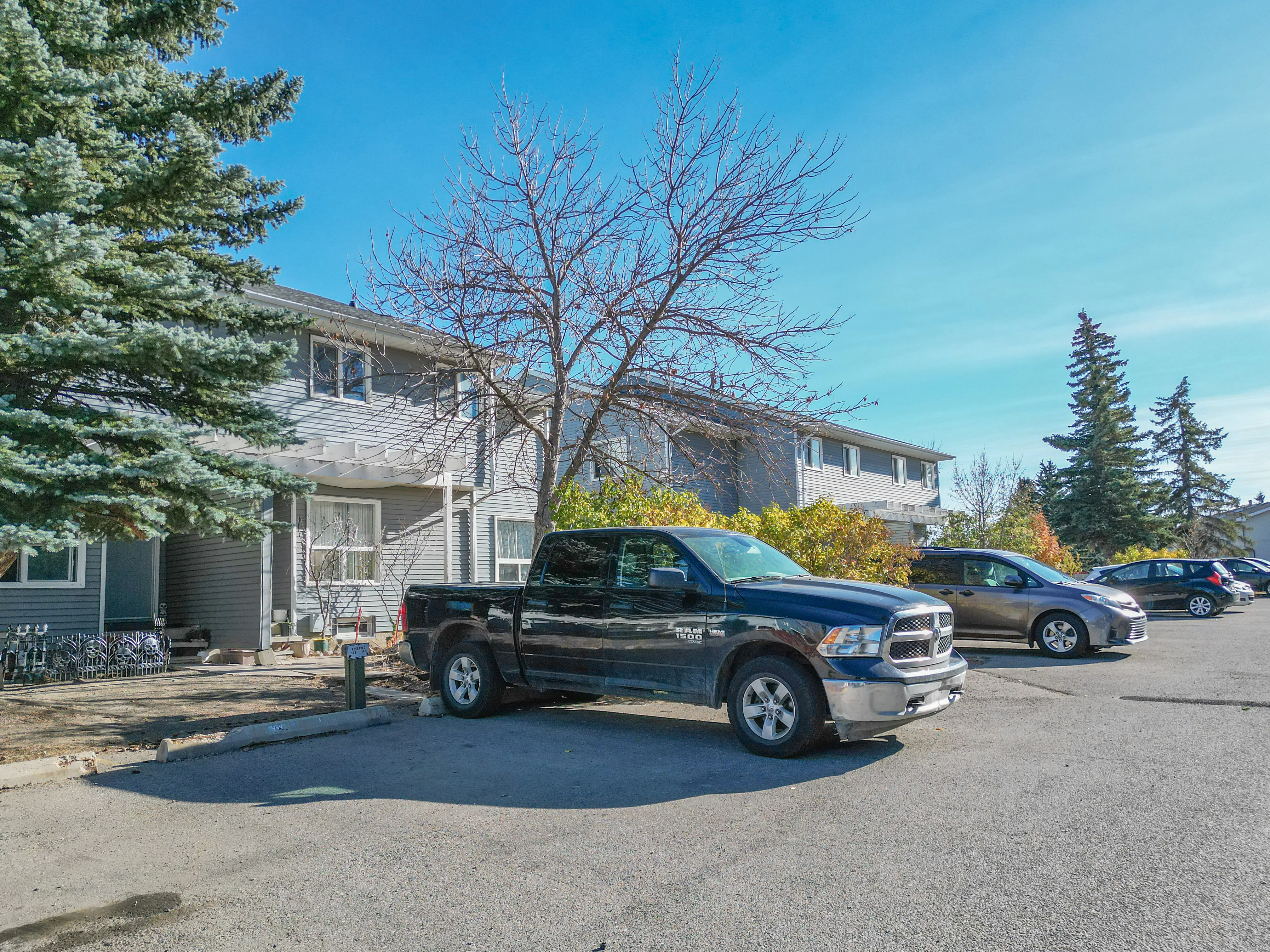 Two-storey multi-unit building with parking and mature trees