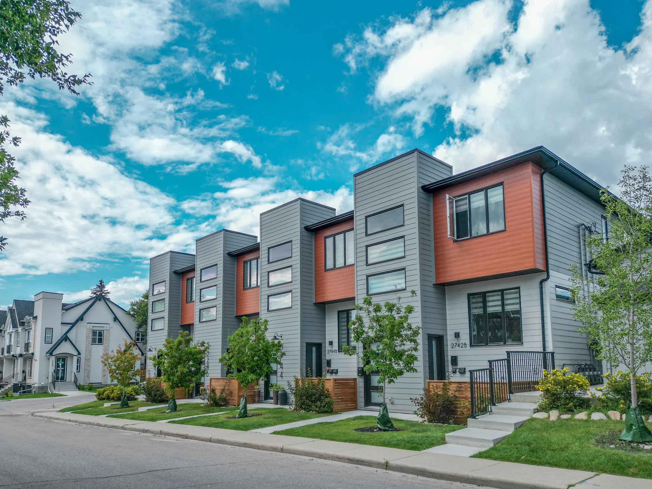 New modern rowhouses with dark and wood-look siding on an inner-city corner