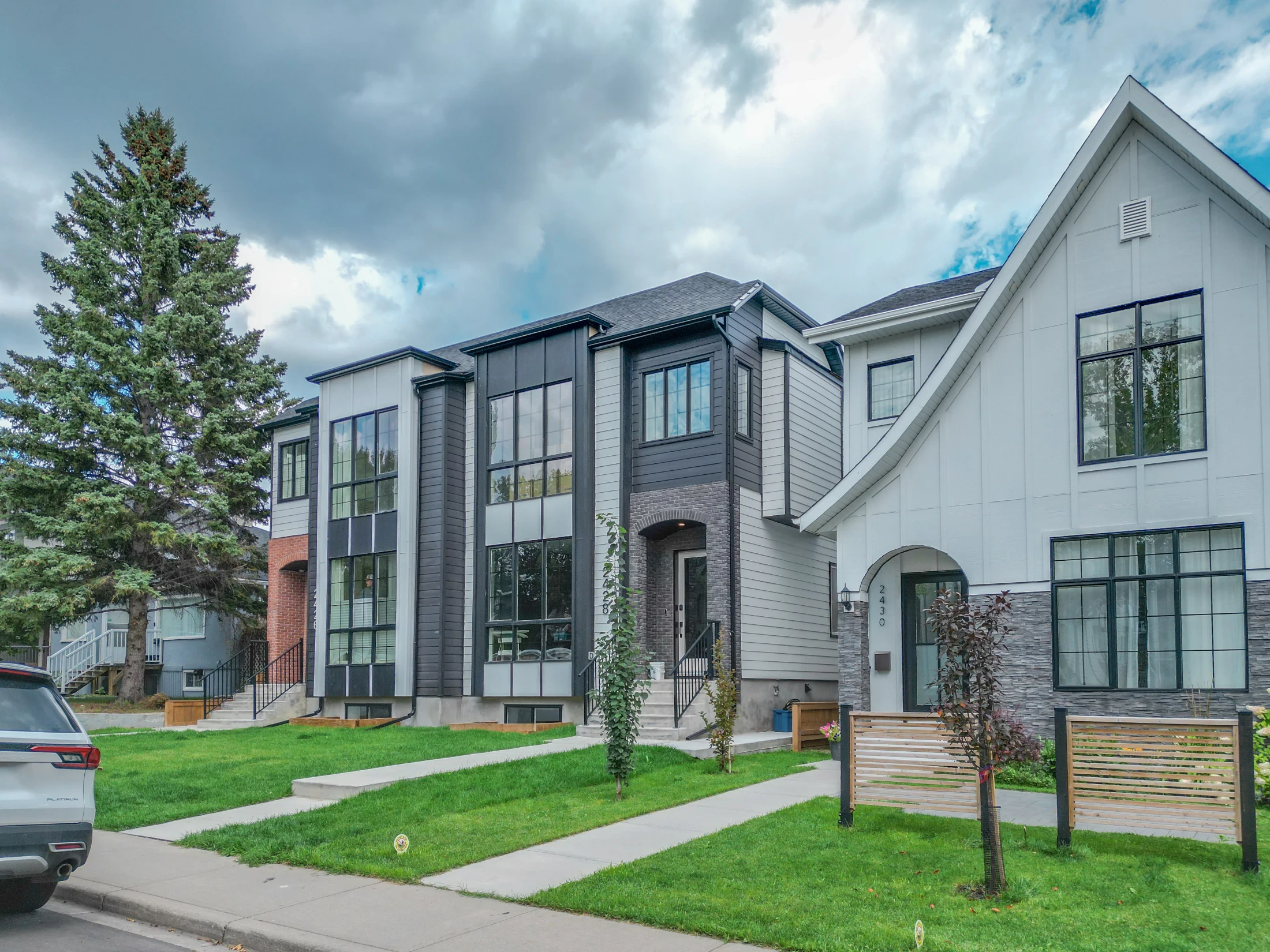 New modern infill home beside a character house on a tree-lined street