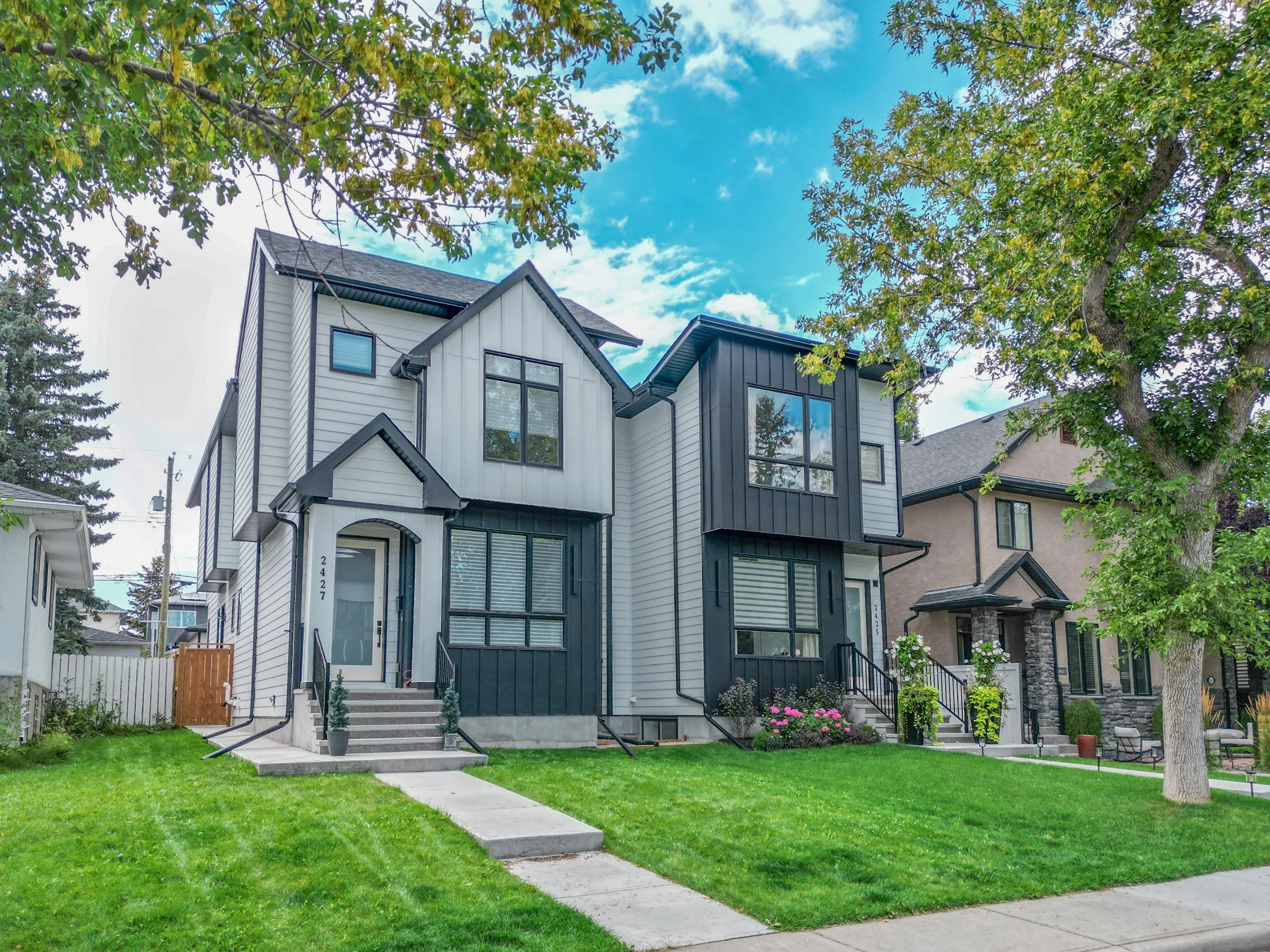 New two-storey infill home with white siding on an established street