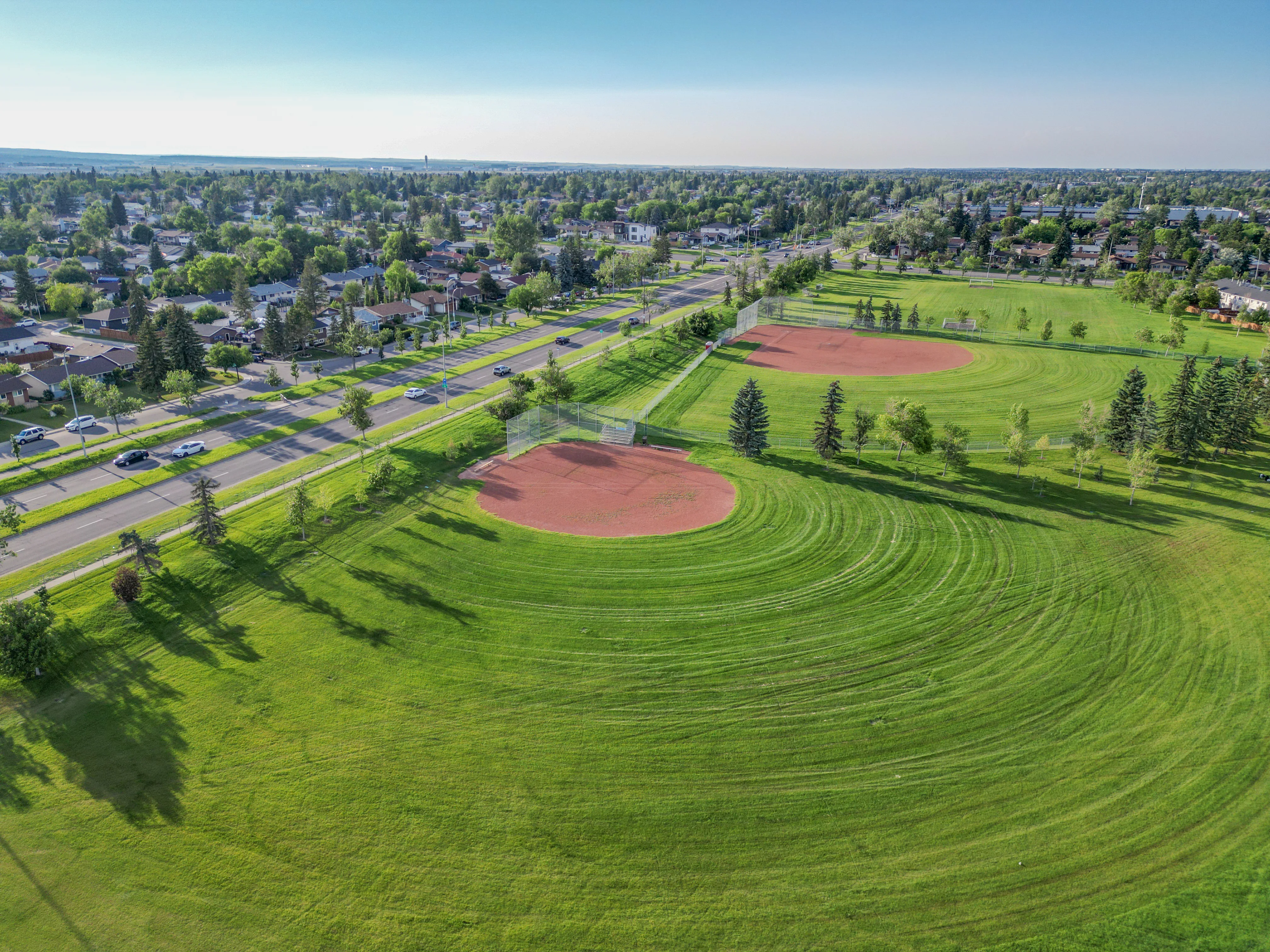 Grass sports fields and a ball diamond lined with trees