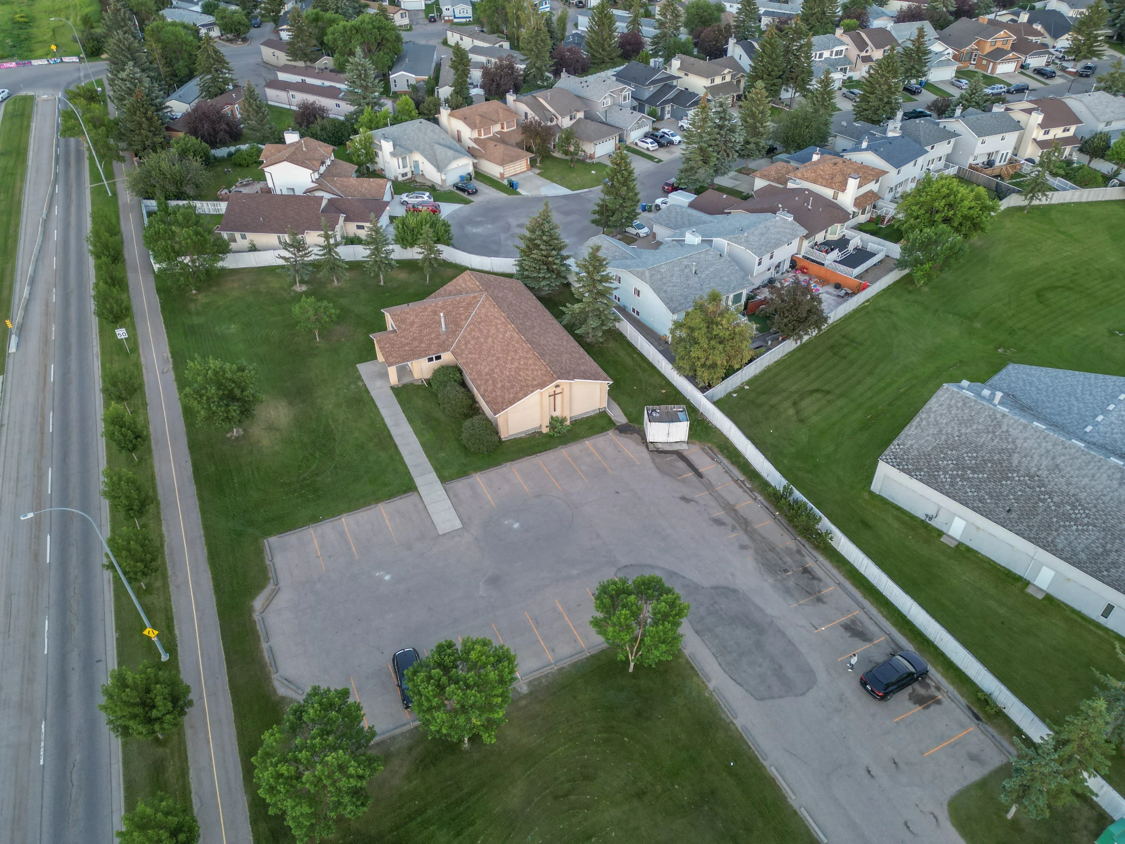 Aerial of a green space beside older homes and a parking lot