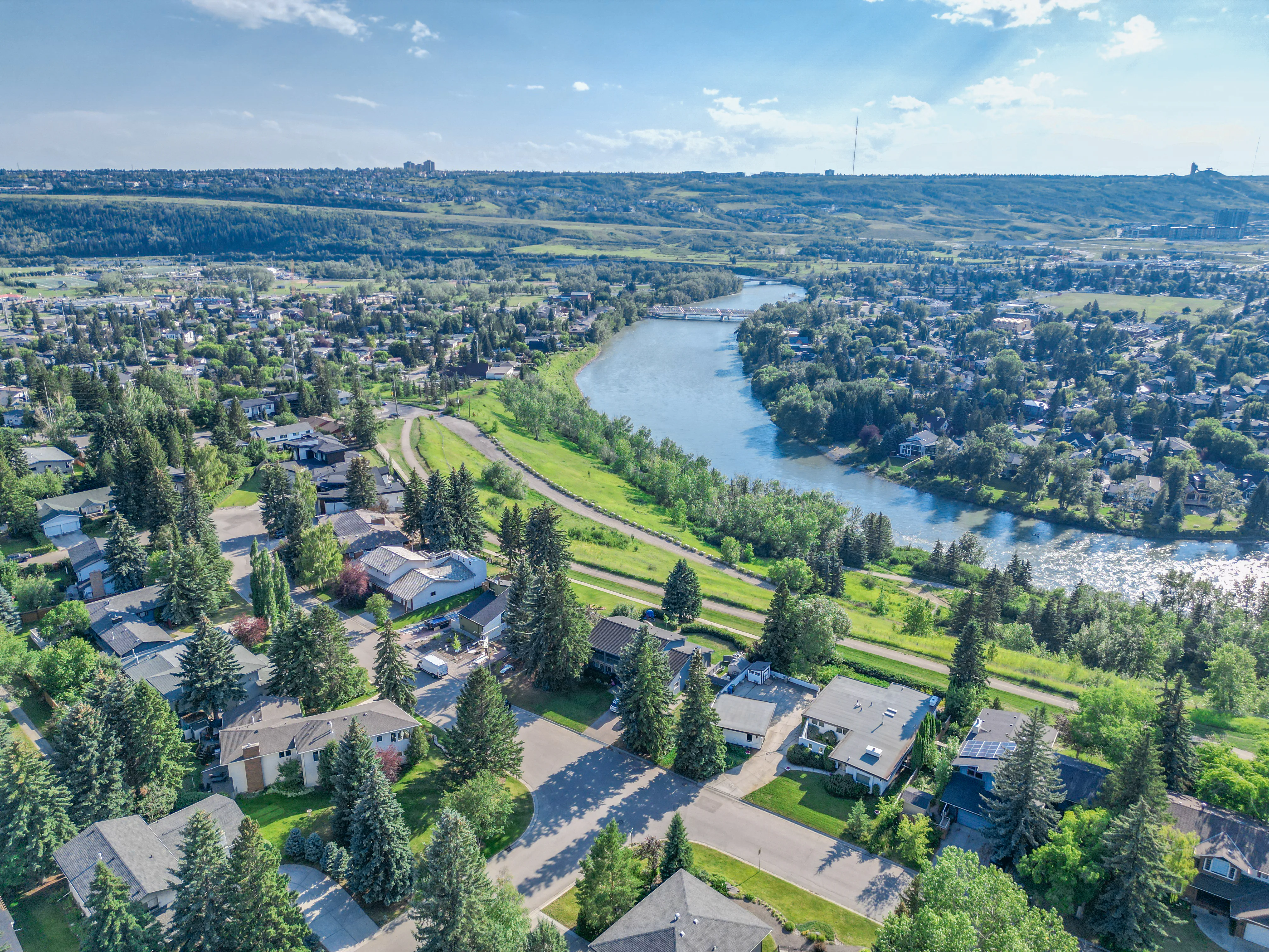 Older homes and tall trees along the Bow River valley in northwest Calgary