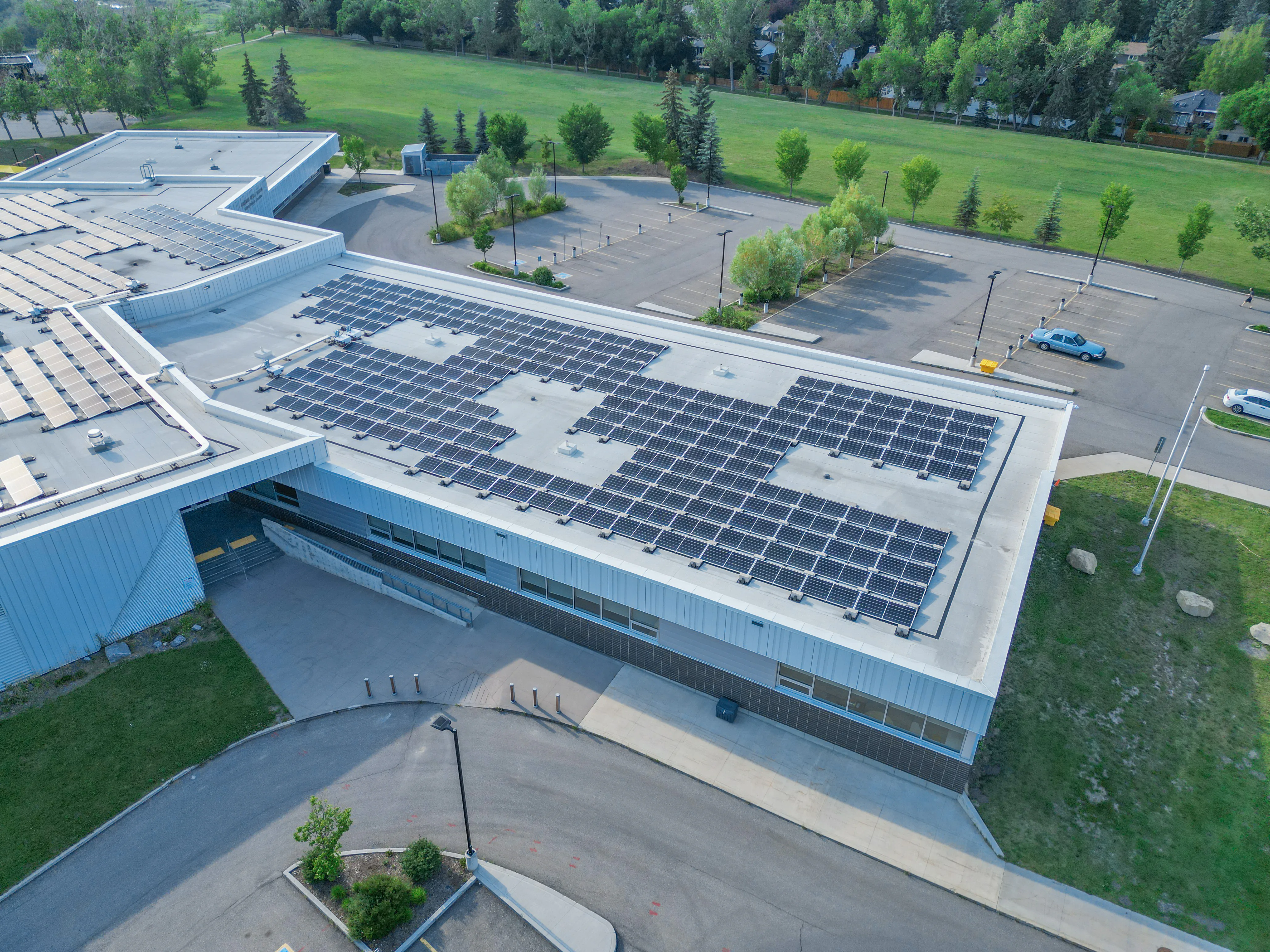 Aerial view of a school building and sports fields in an established northwest Calgary neighbourhood