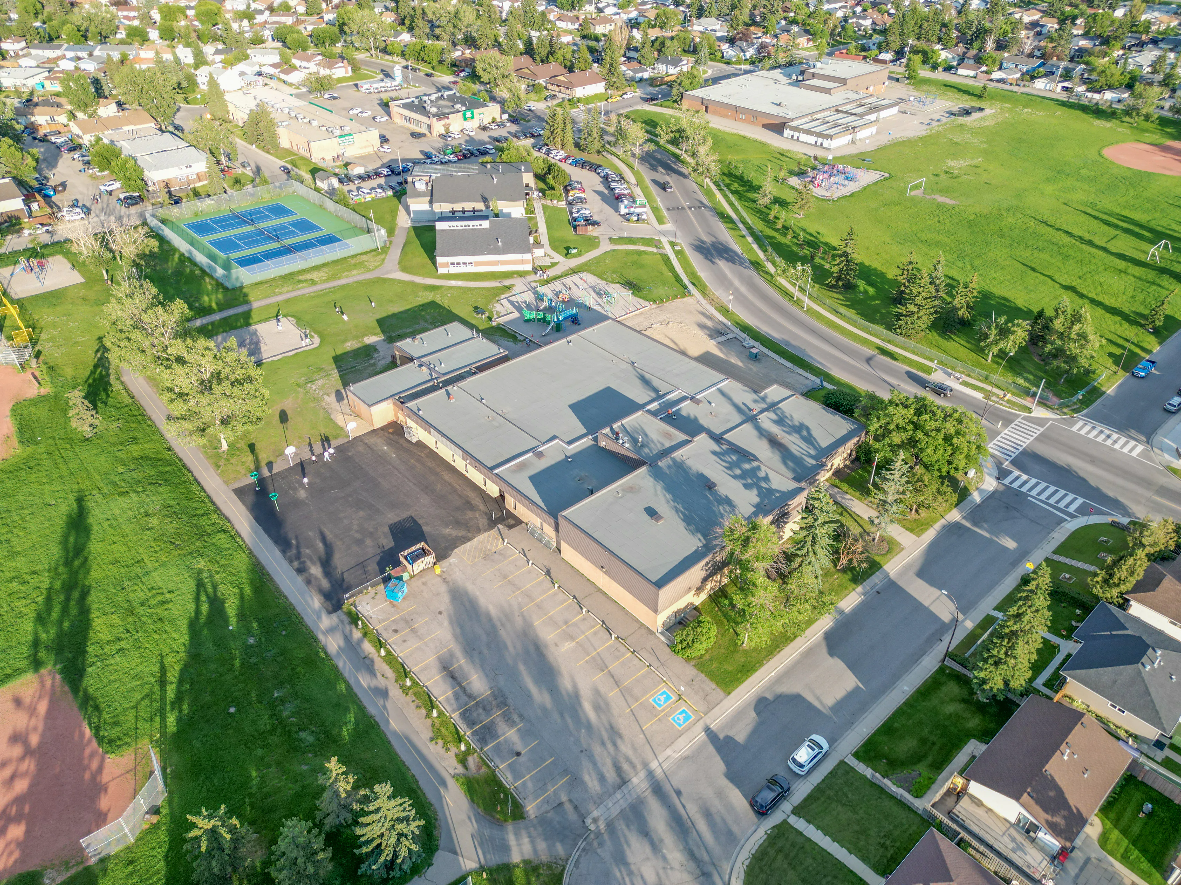 Aerial of tennis courts, a school and nearby homes