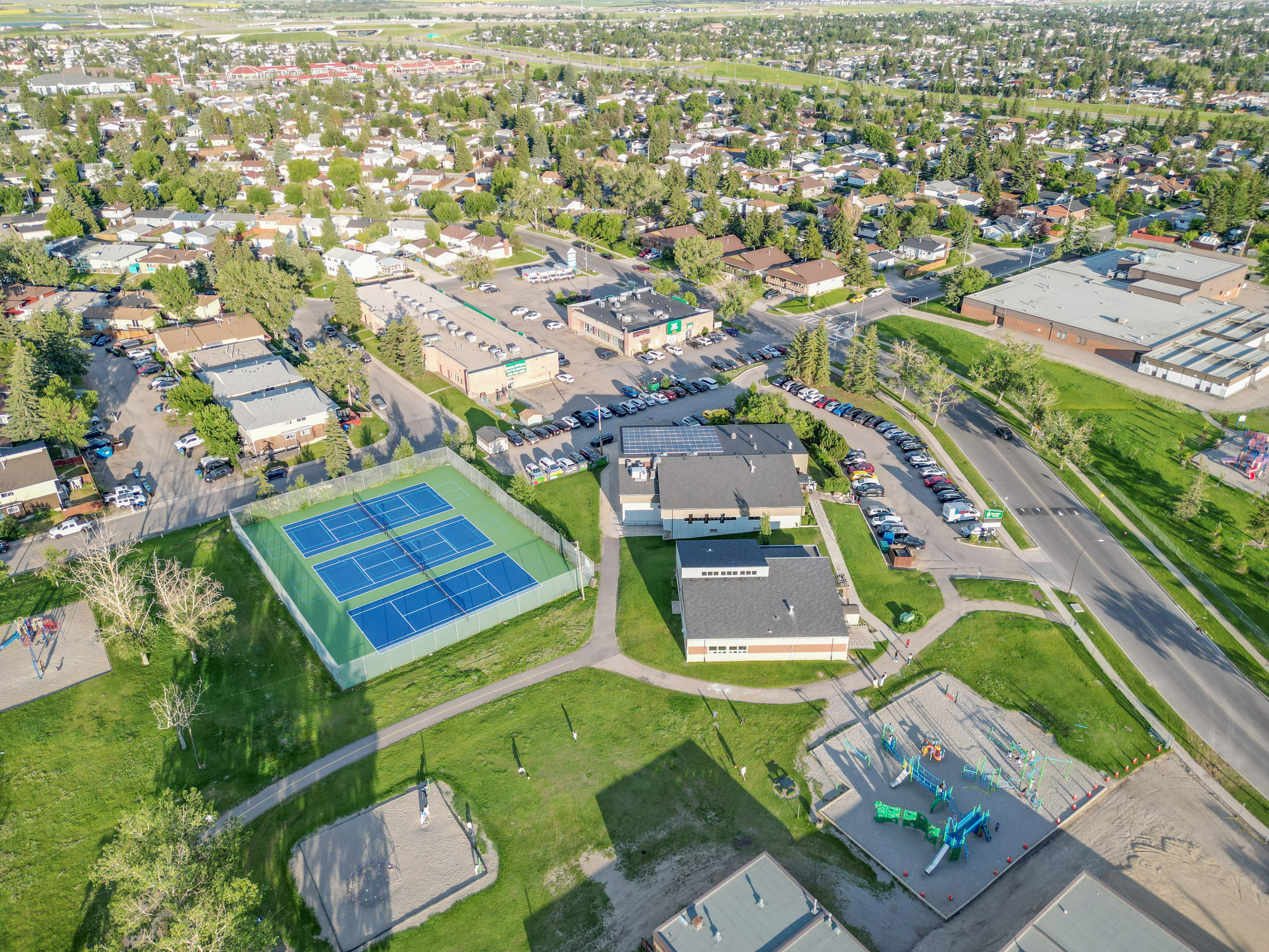 Aerial of tennis courts and green space among homes