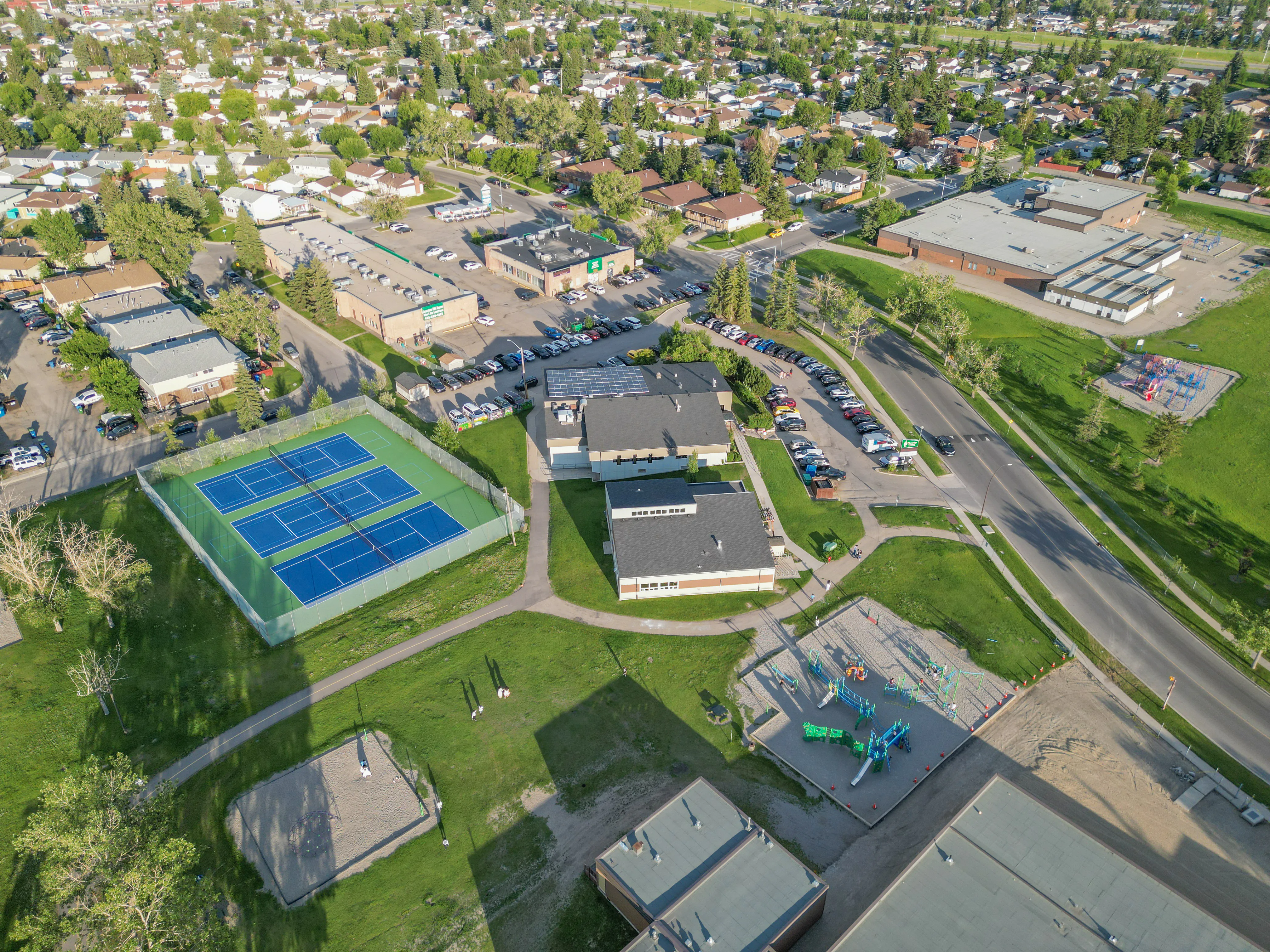 Aerial of tennis courts and a park next to homes
