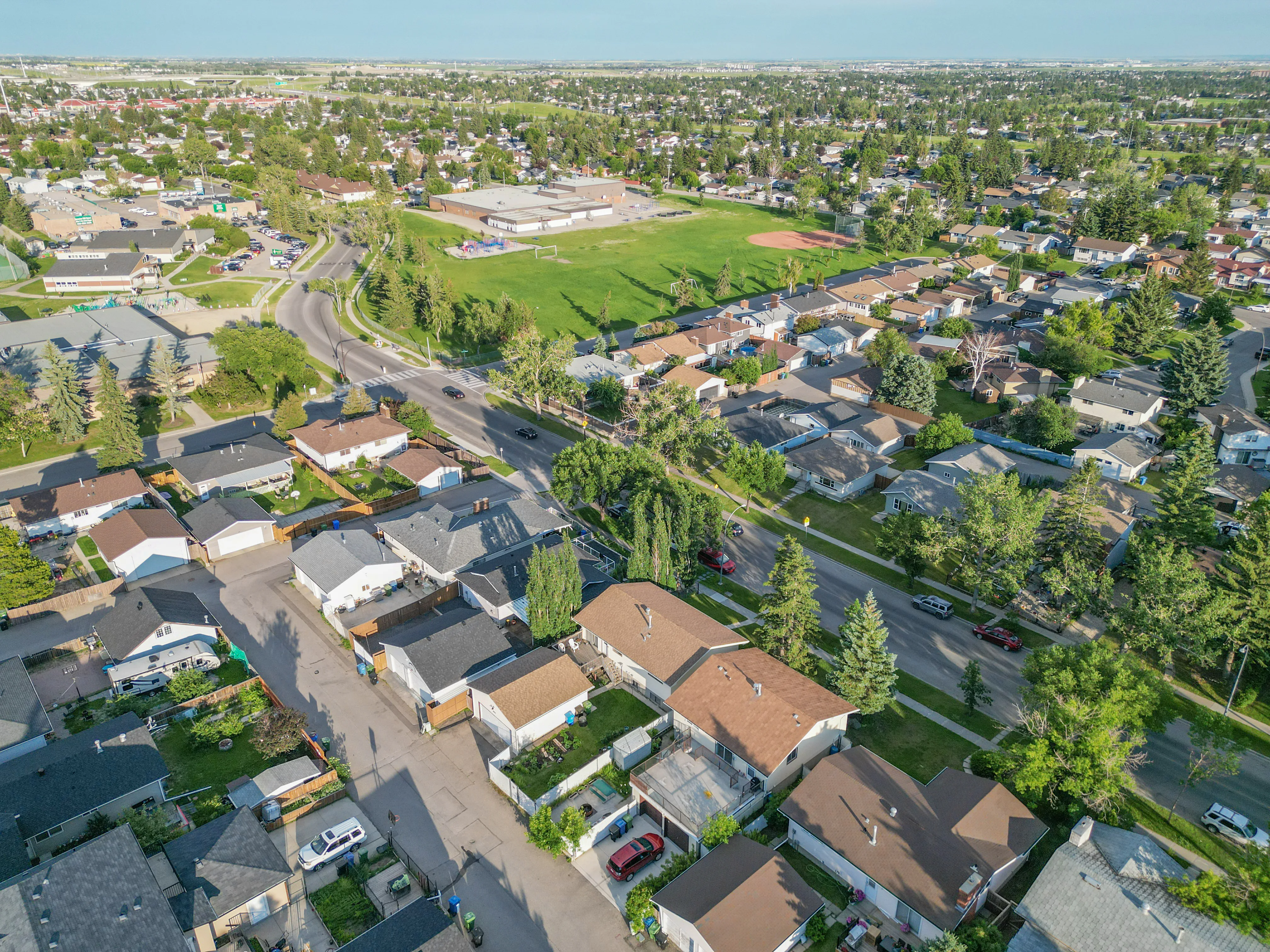 Aerial of homes on winding streets with a green field