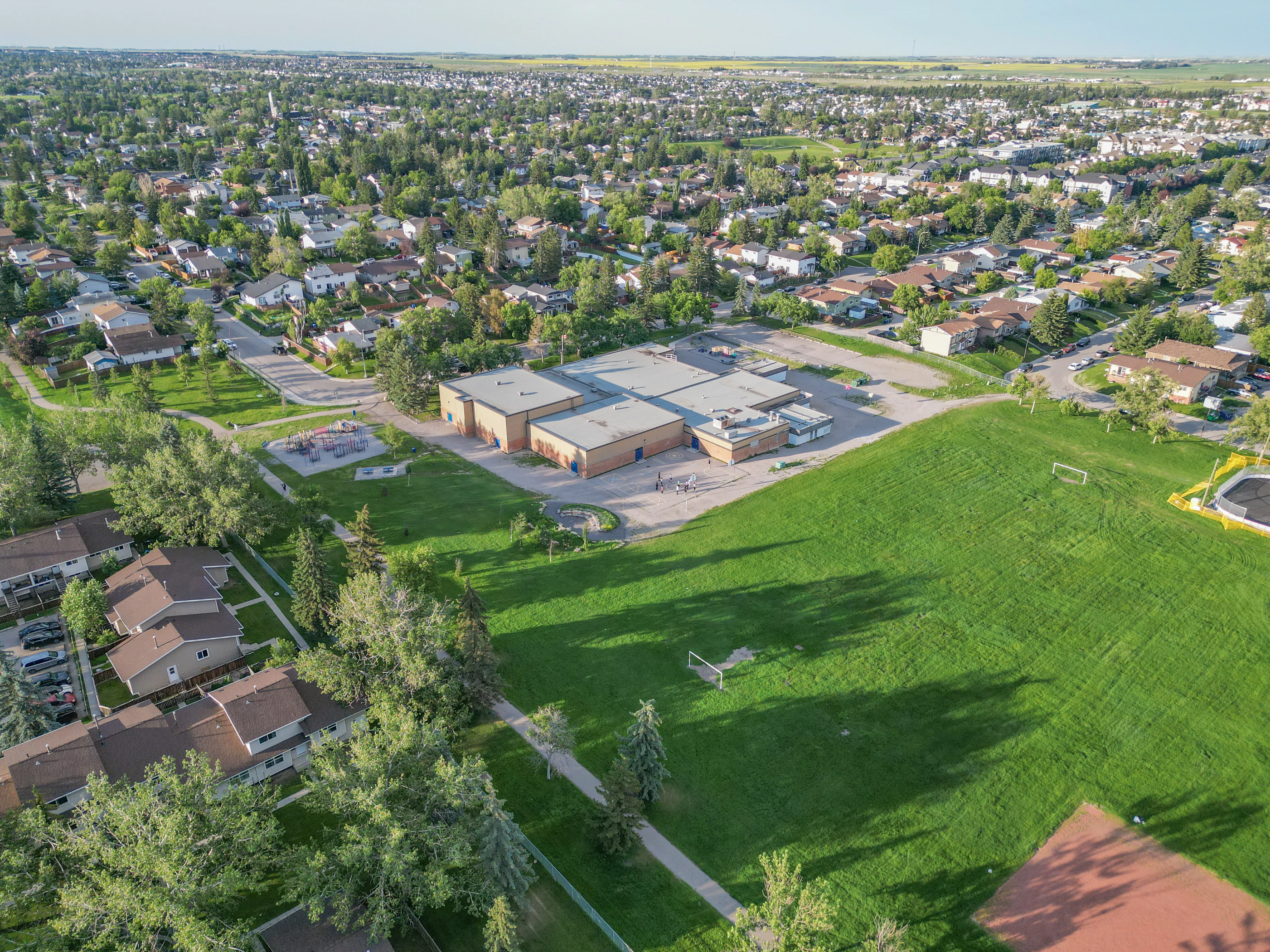 Aerial of homes beside a large green field and school