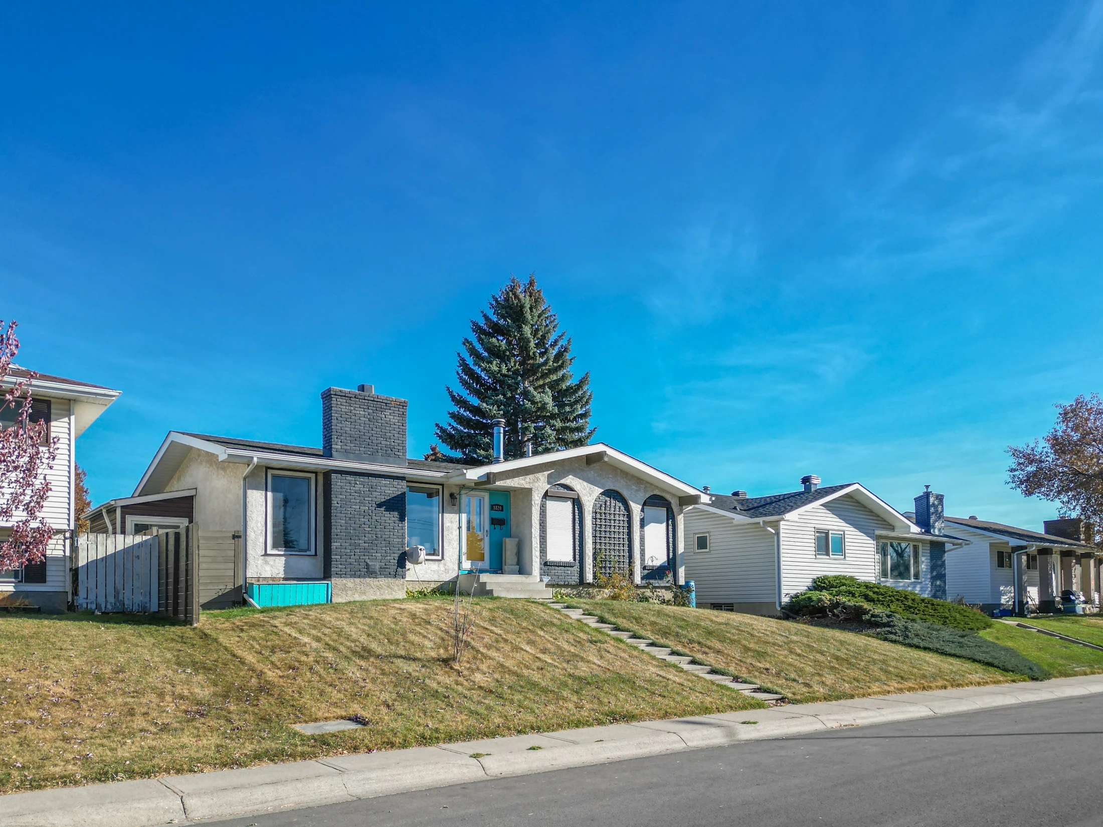 Bungalow with a red-trimmed roof on a quiet residential street