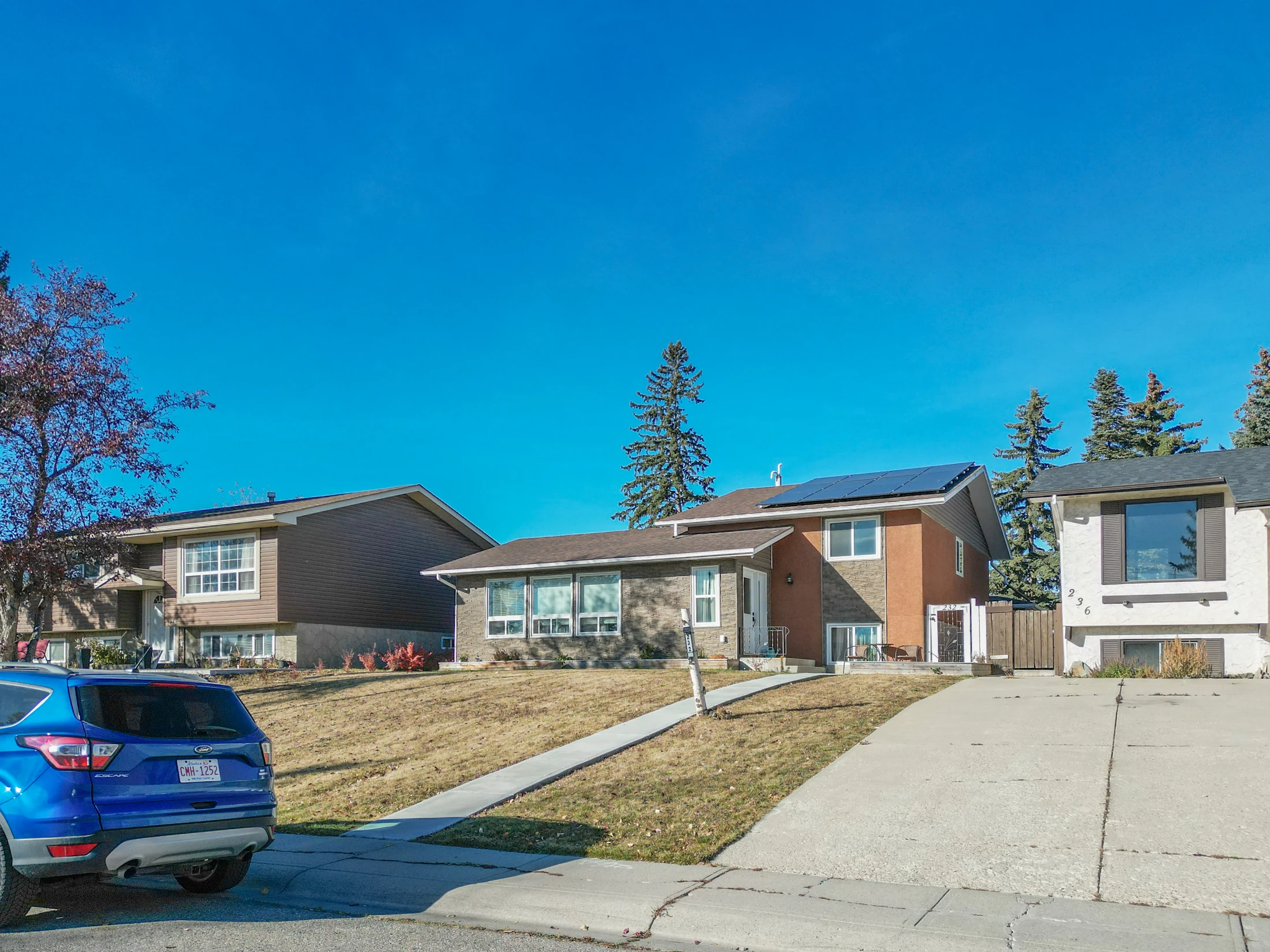 Raised bungalow with a front lawn and a parked car