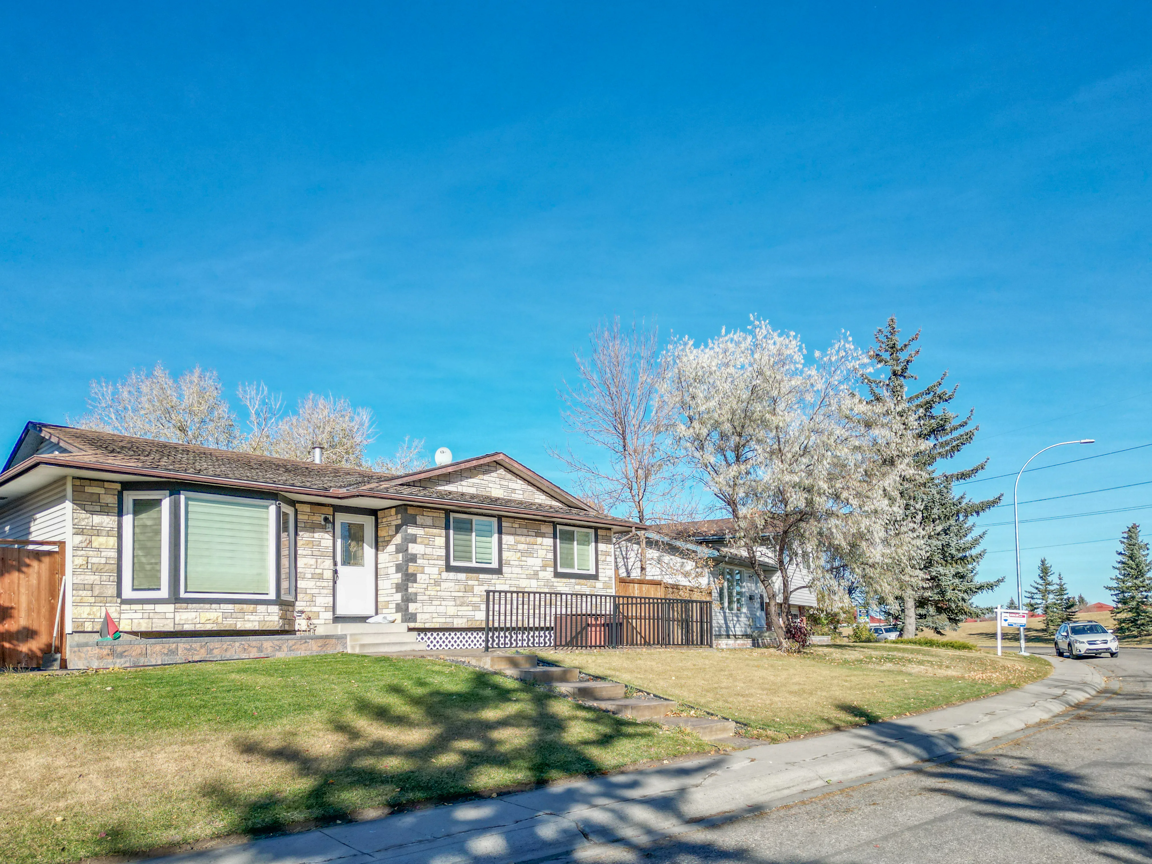 Bungalow with a flowering tree and a front lawn on a residential street