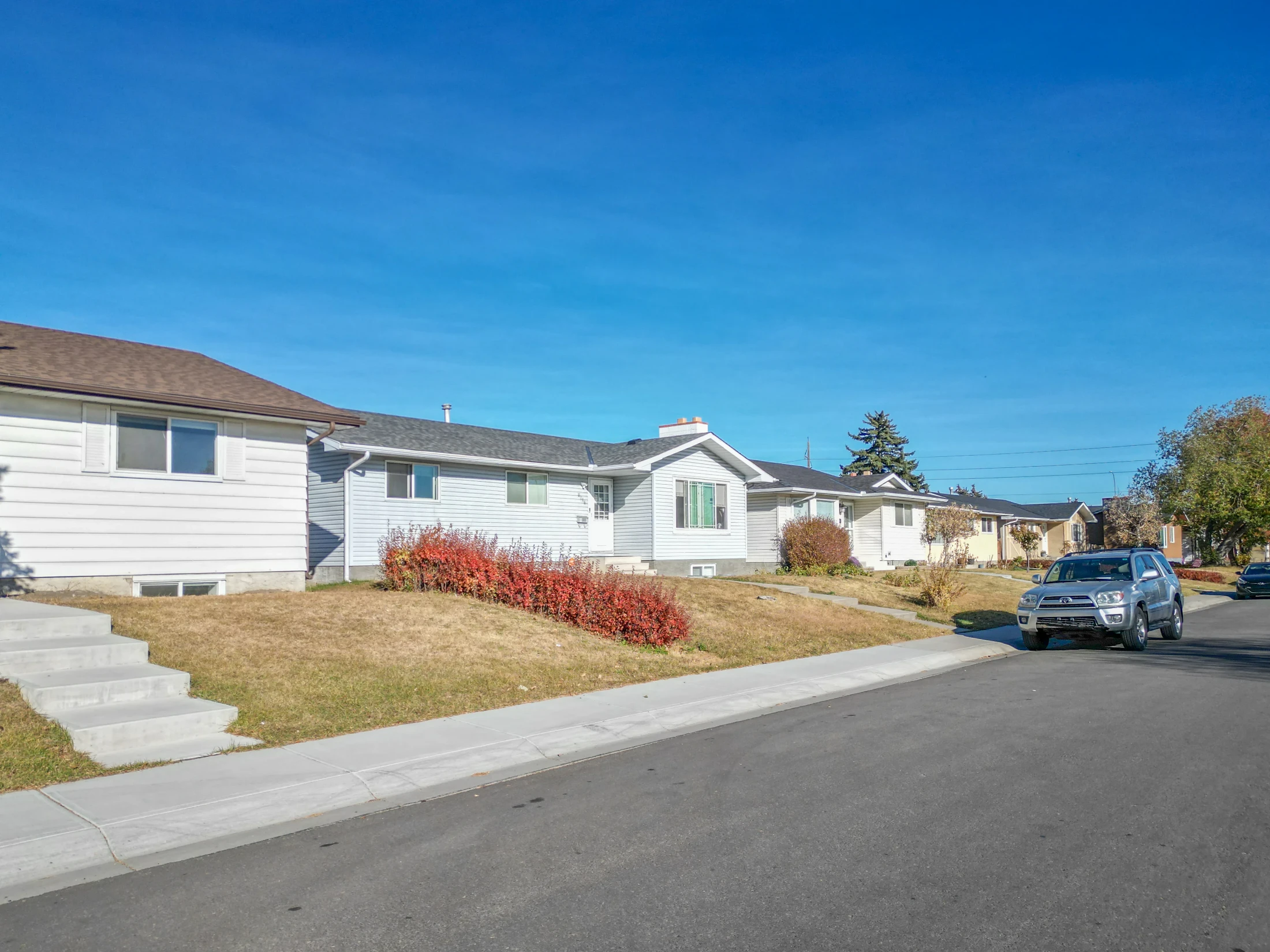 Bi-level homes with lawns along a sunny residential street