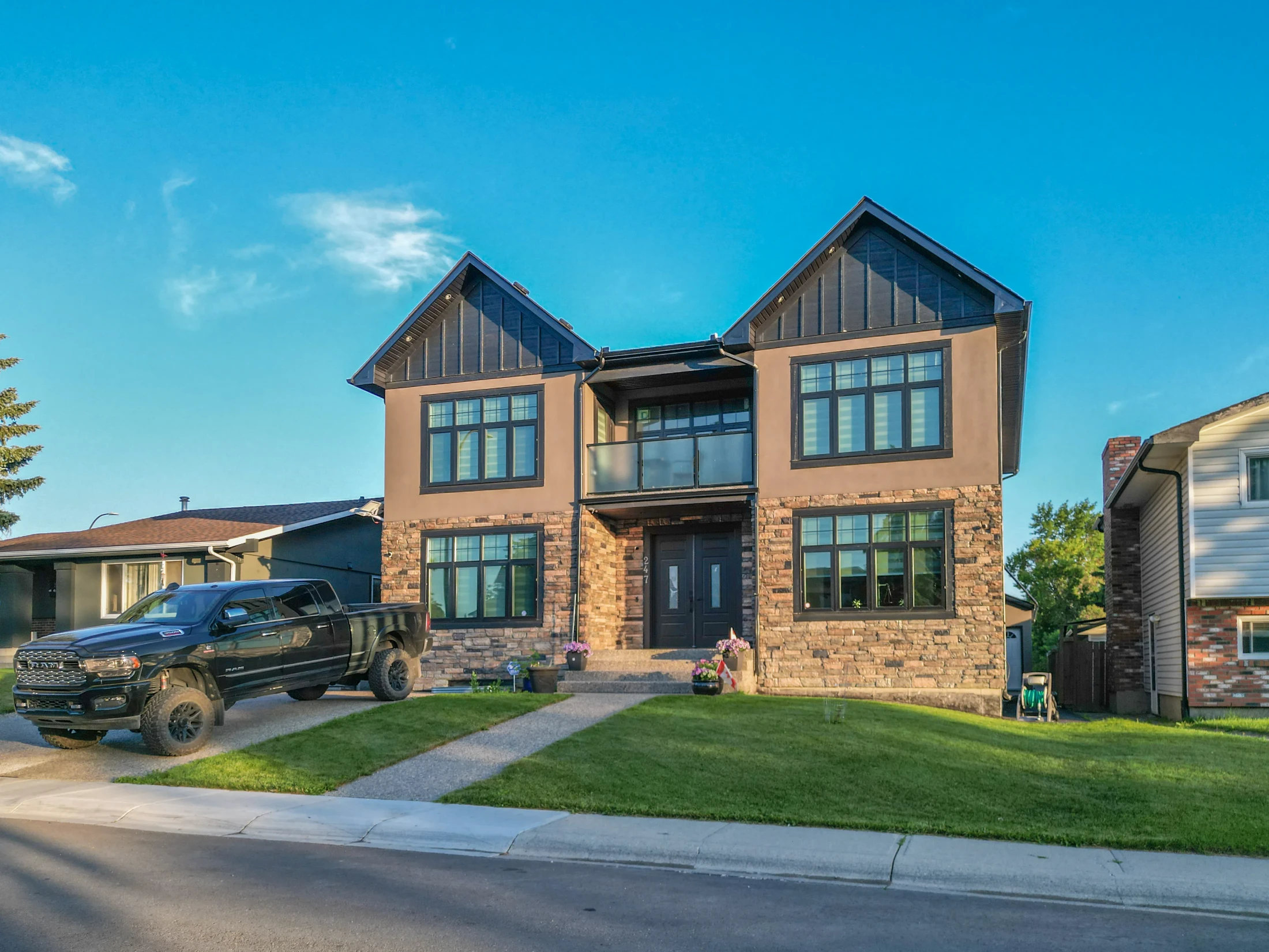 Modern two-storey infill with dark siding and a front lawn