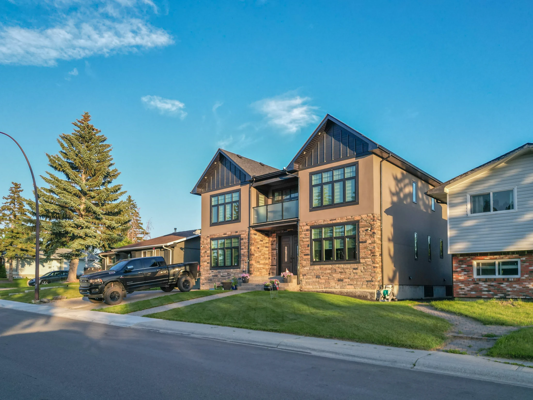 New two-storey infill with stone and siding beside a split-level home
