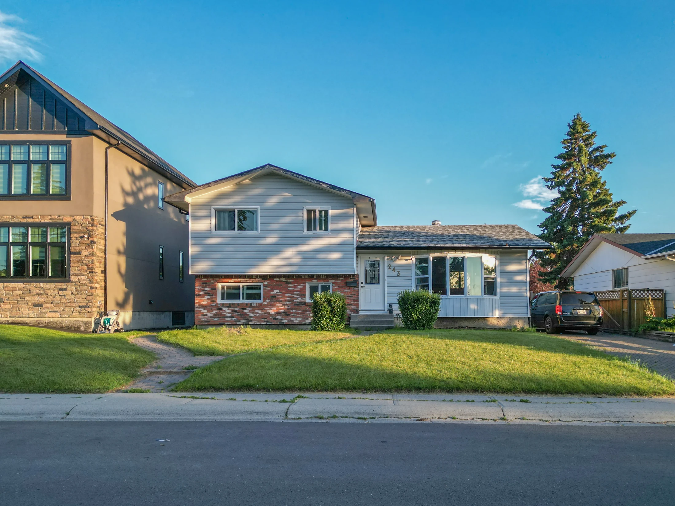 New infill with stone accents beside an older split-level home