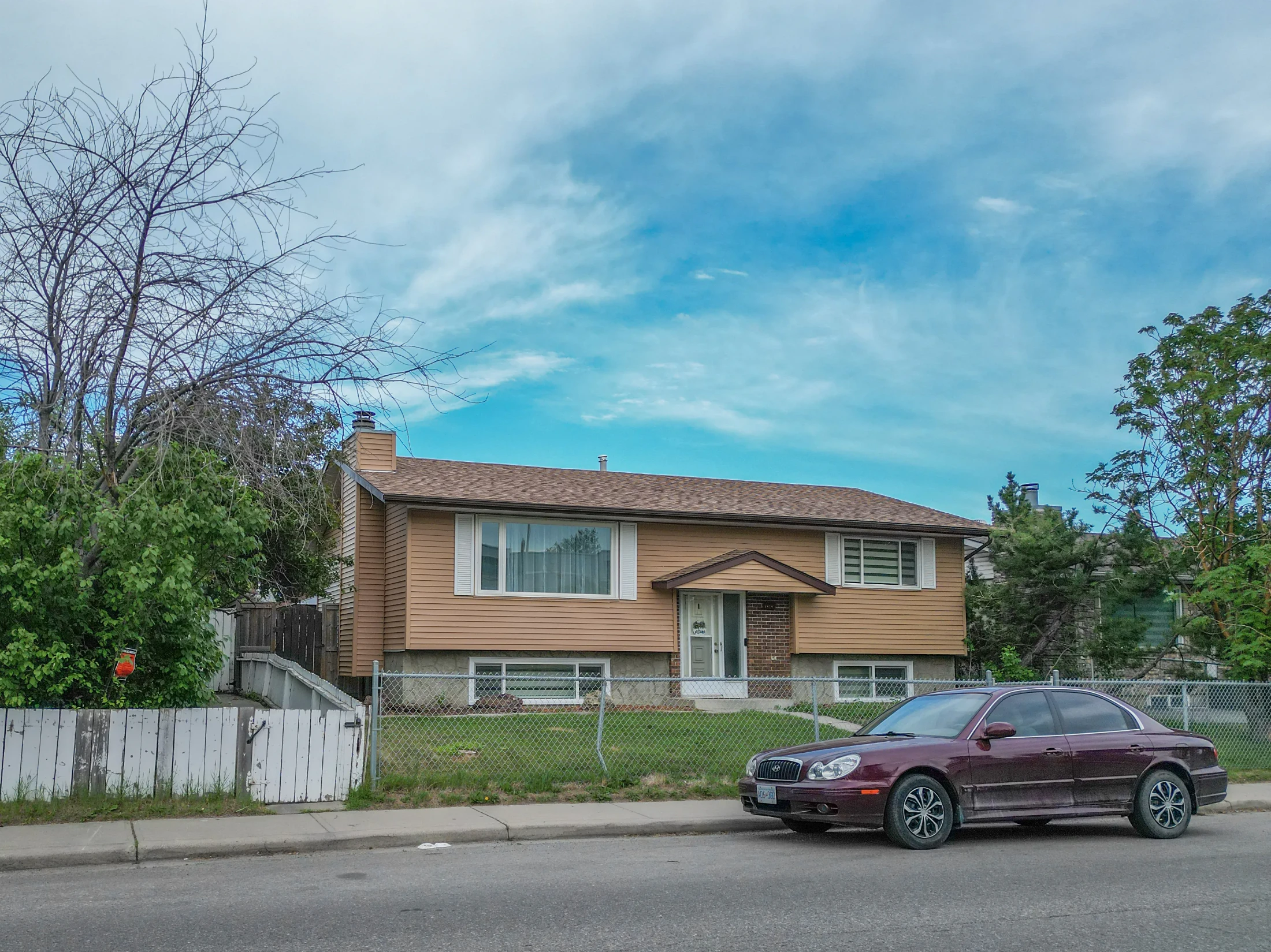 Older bungalow with a front lawn and a mature tree