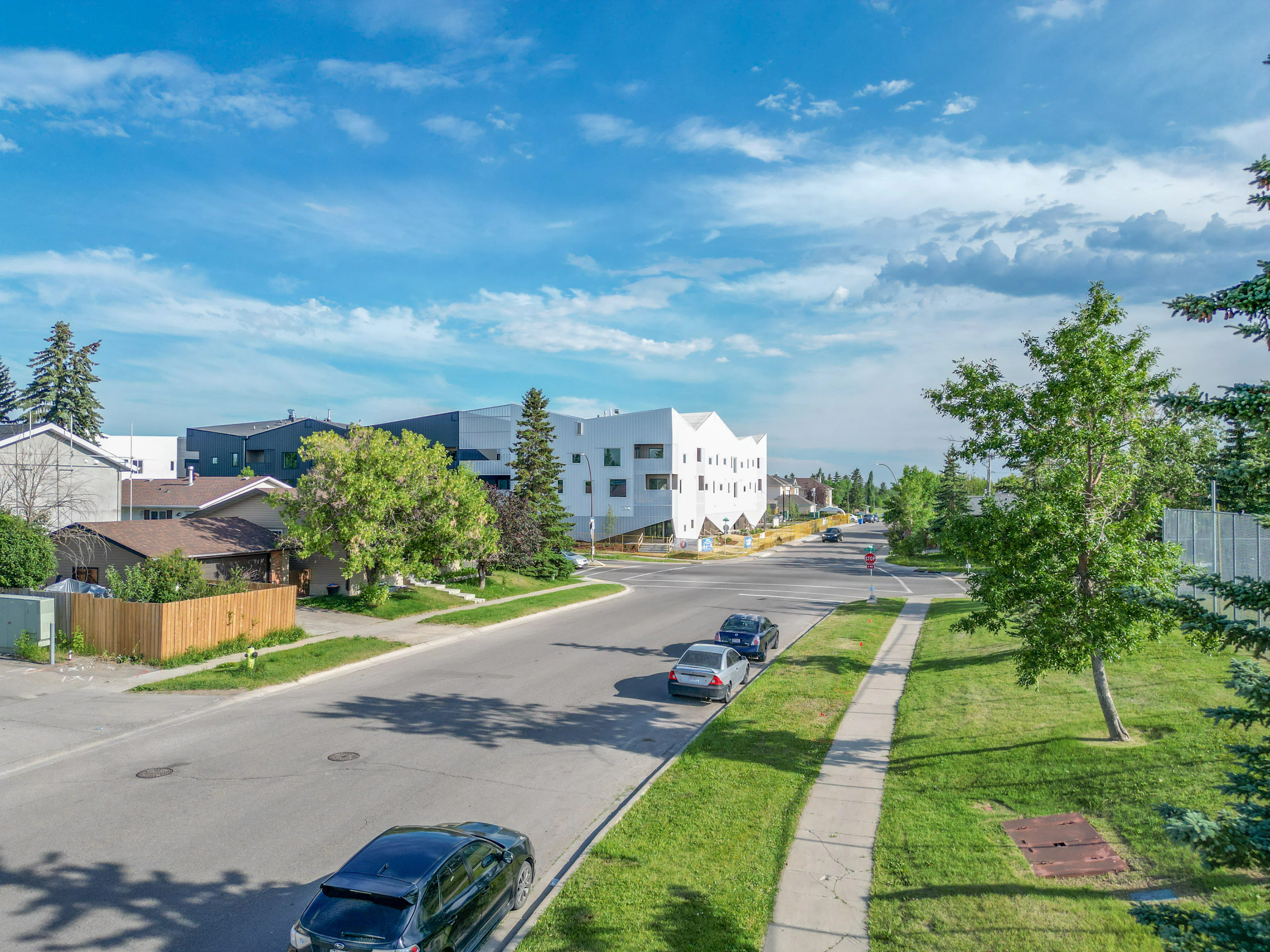 Residential street with a white apartment building and trees