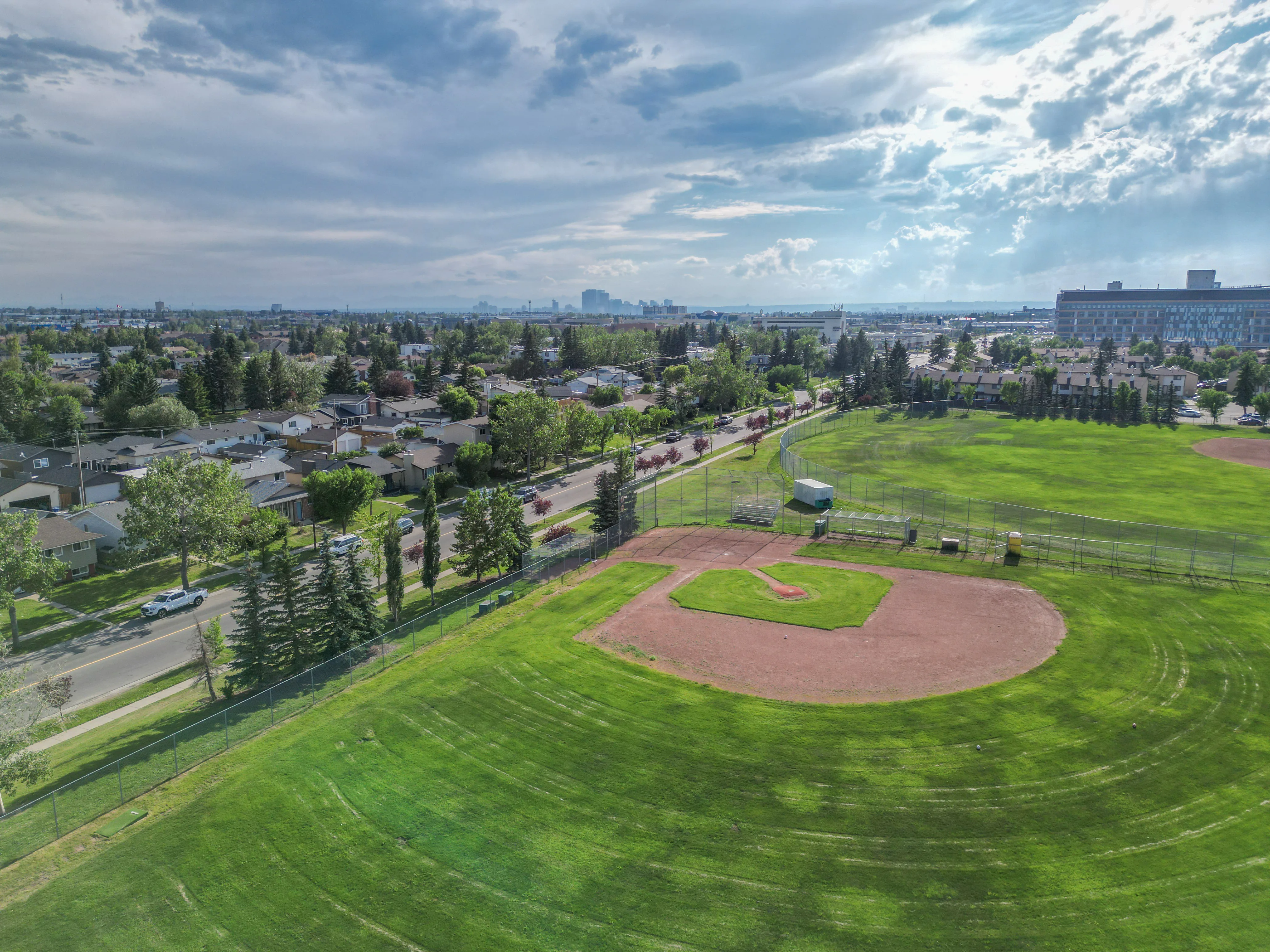 Aerial of a ball diamond and green field with homes around it